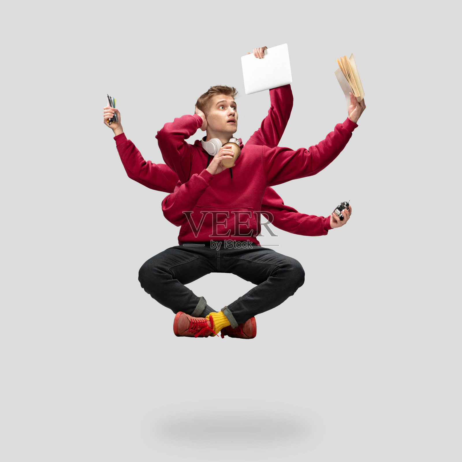 英俊的多臂学生悬浮孤立在灰色工作室背景与设备照片摄影图片