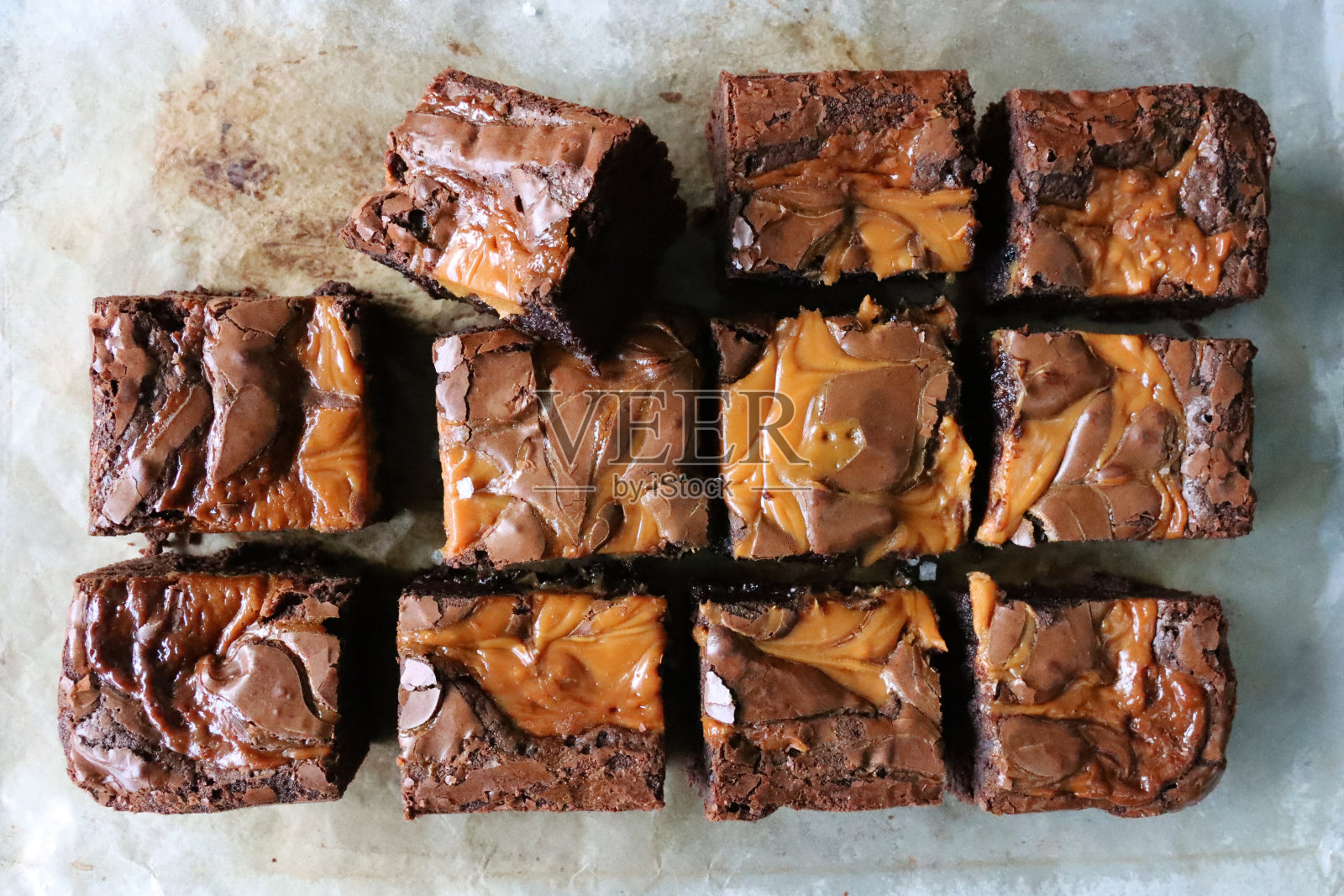 自制巧克力盐焦糖布朗尼方块在防油烘焙纸上,俯瞰照片摄影图片