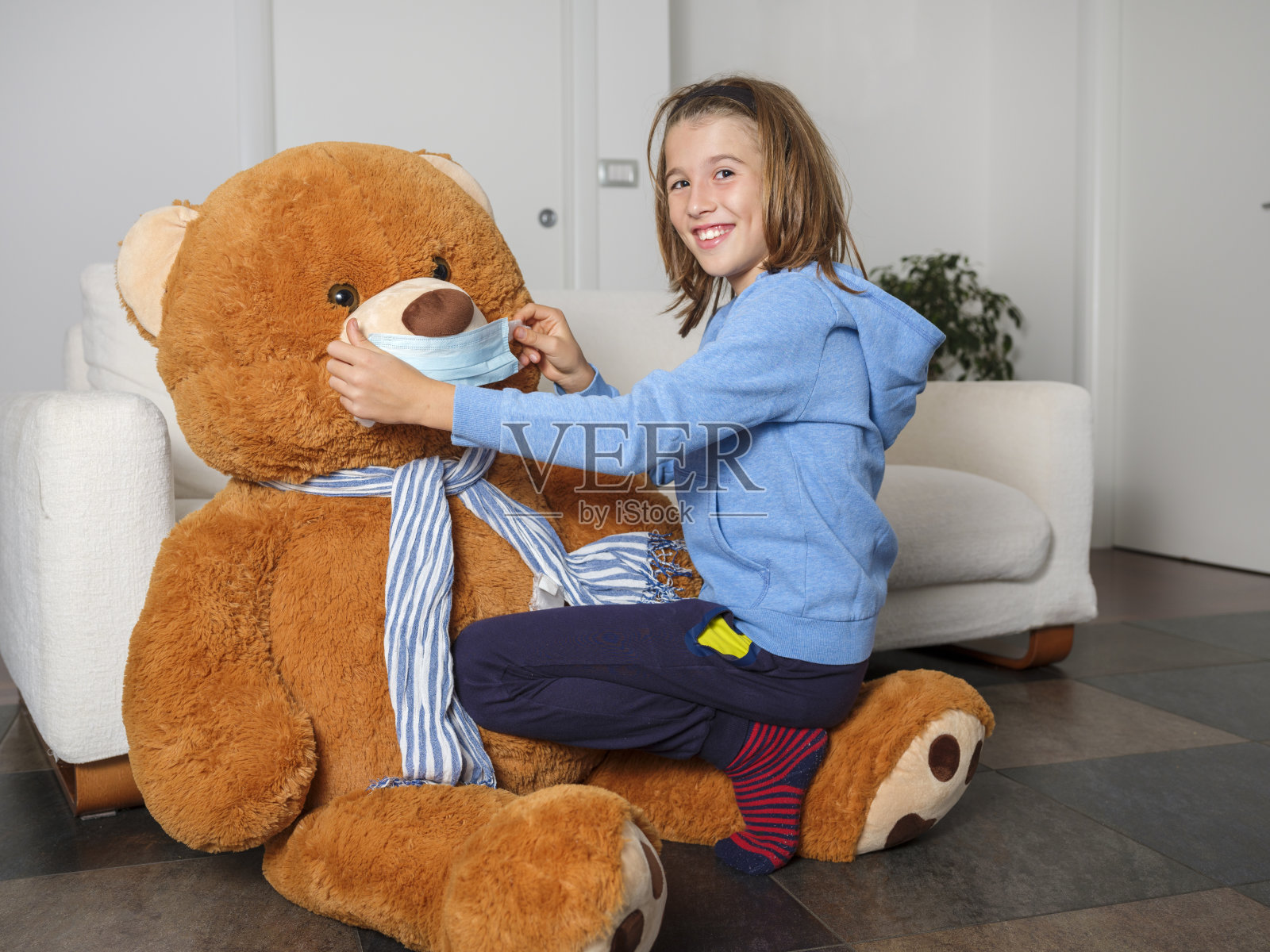 孩子在家里用笔记本电脑上课,坐在沙发上,带着口罩的泰迪熊保护自己不受冠状病毒感染照片摄影图片