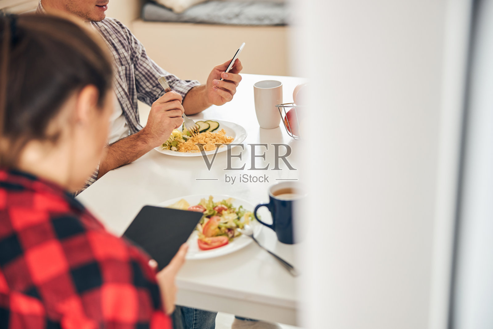 一名男子和他的女性配偶在午餐时使用电子产品照片摄影图片