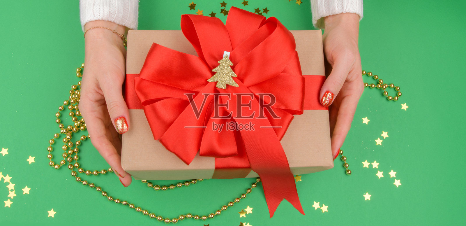 女性手握礼品与红色蝴蝶结在白色的乡村背景。节日背景:生日,情人节,圣诞节,新年。平躺风格照片摄影图片