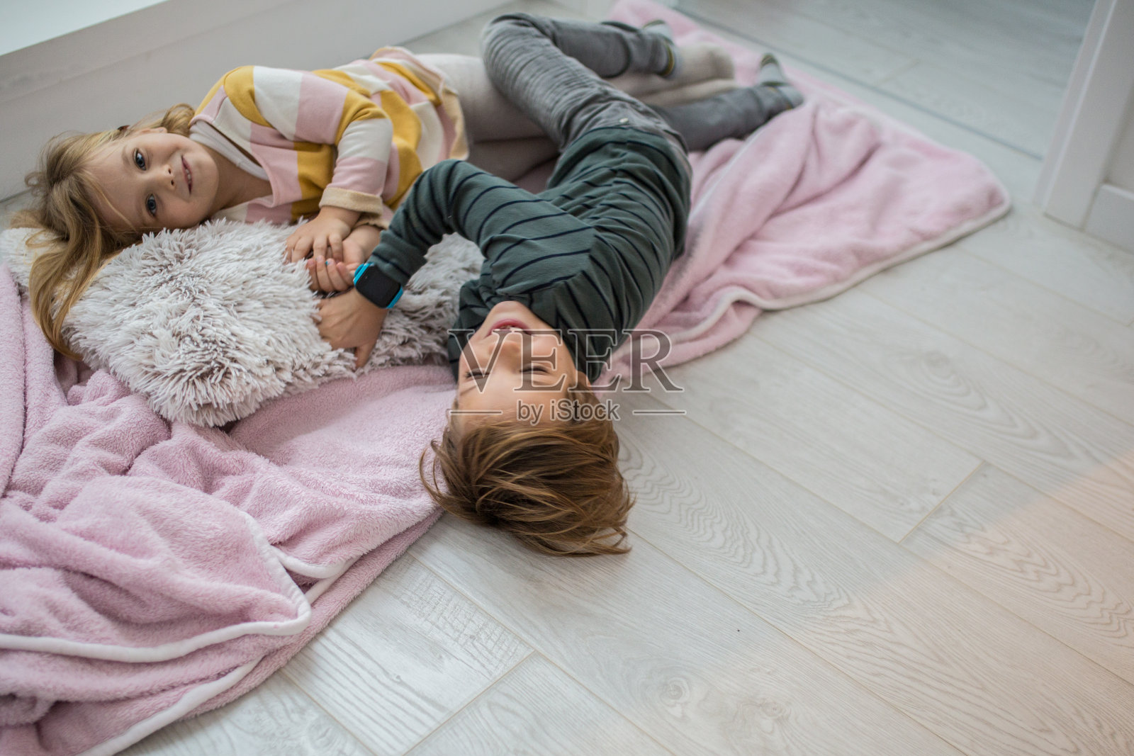 两个小孩躺在家里的地板上照片摄影图片
