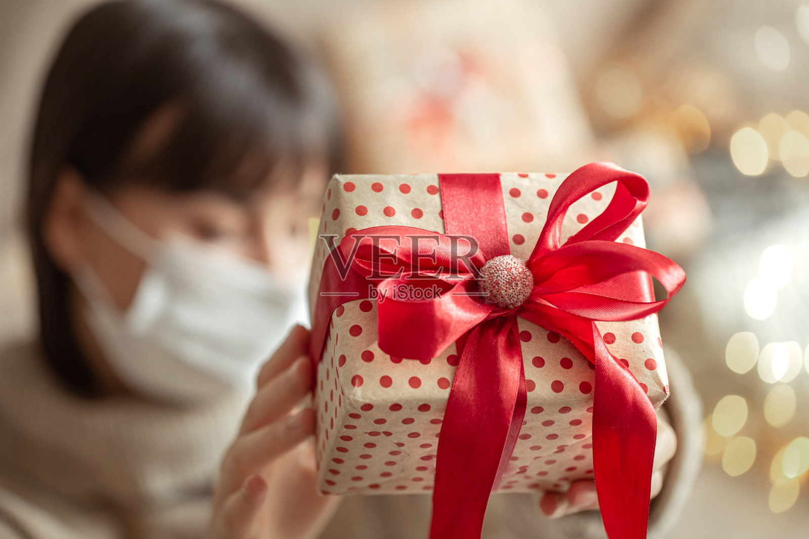 女孩戴着面具,近距离拿着圣诞礼物。照片摄影图片