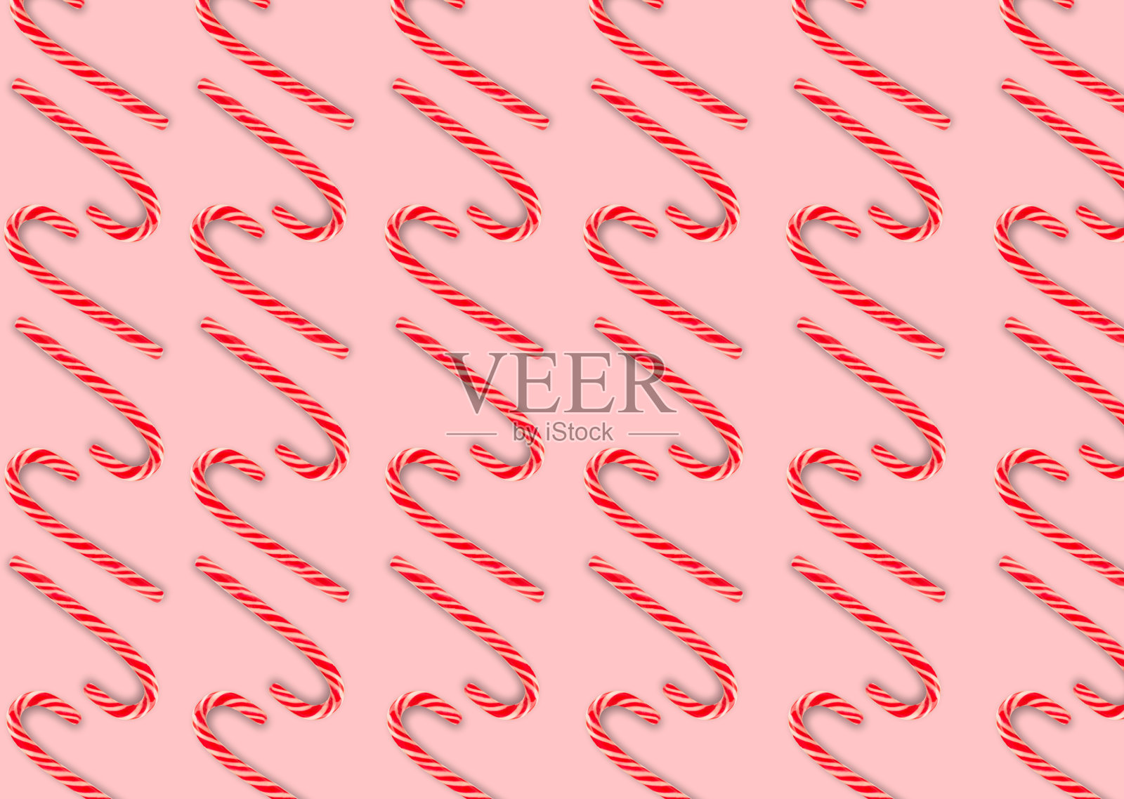 平面构图,粉红色背景上有棒棒糖。糖果手杖条纹图案在圣诞节的颜色。红白条纹的棒棒糖。圣诞节的背景。糖果店的概念。照片摄影图片