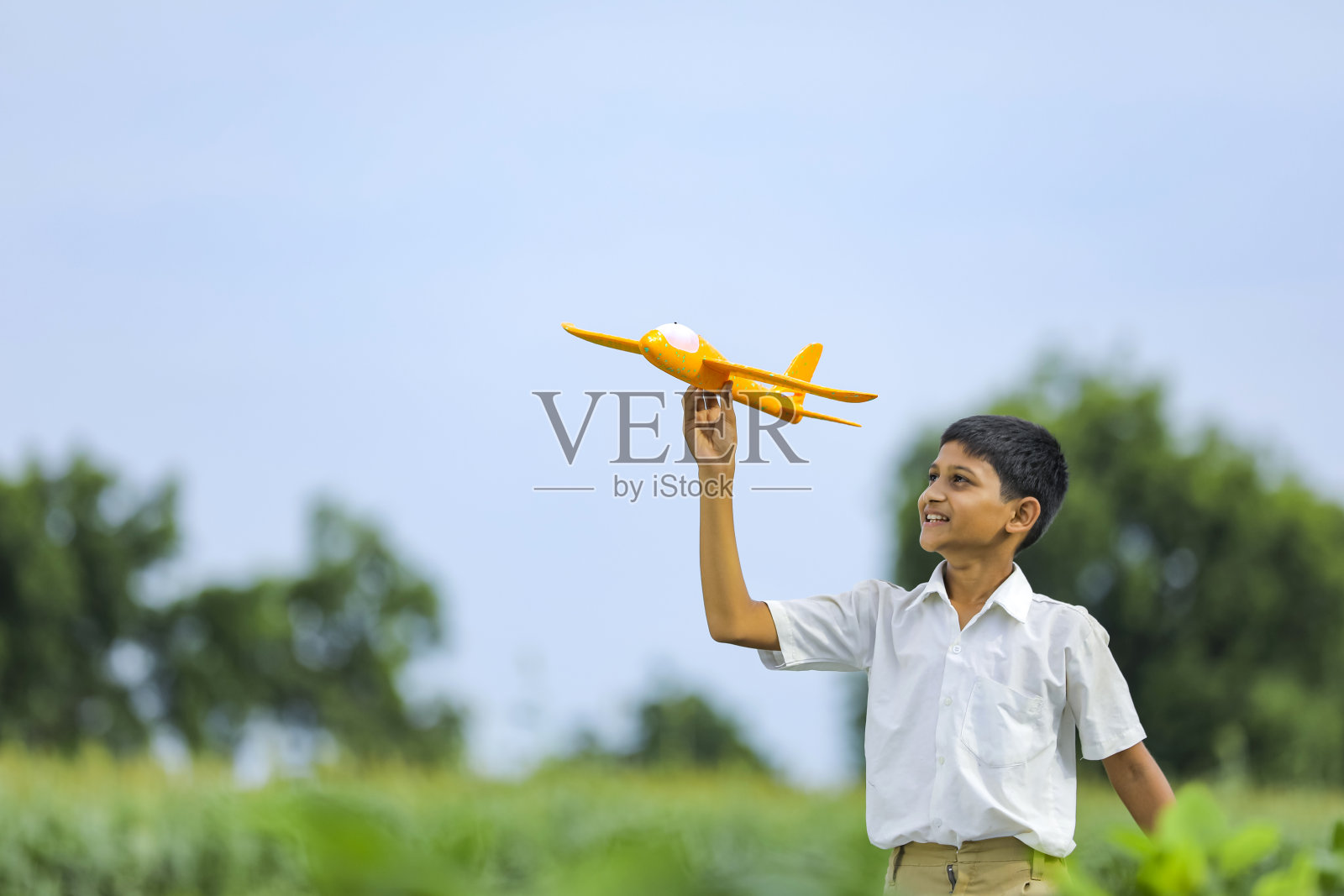 飞行的梦想!在绿地上玩玩具飞机的印度小孩照片摄影图片