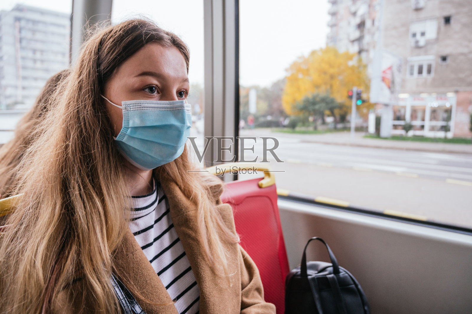 年轻女子戴着面具坐在地铁里照片摄影图片