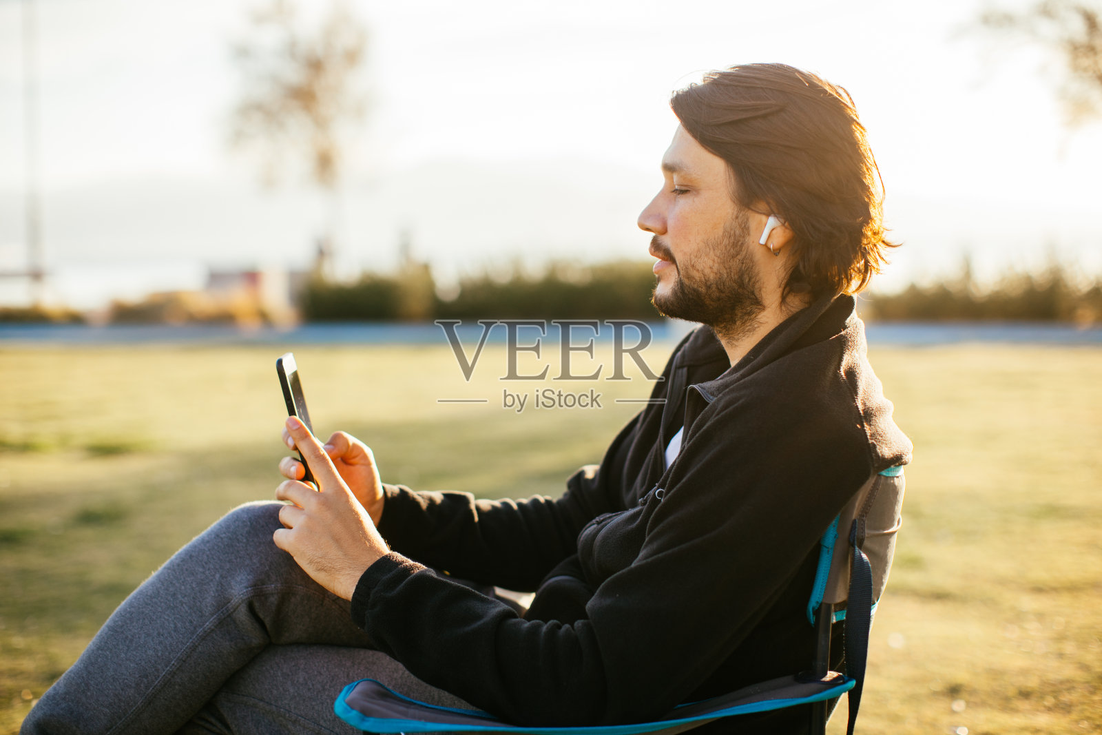 一名男子坐在露营椅上使用手机照片摄影图片