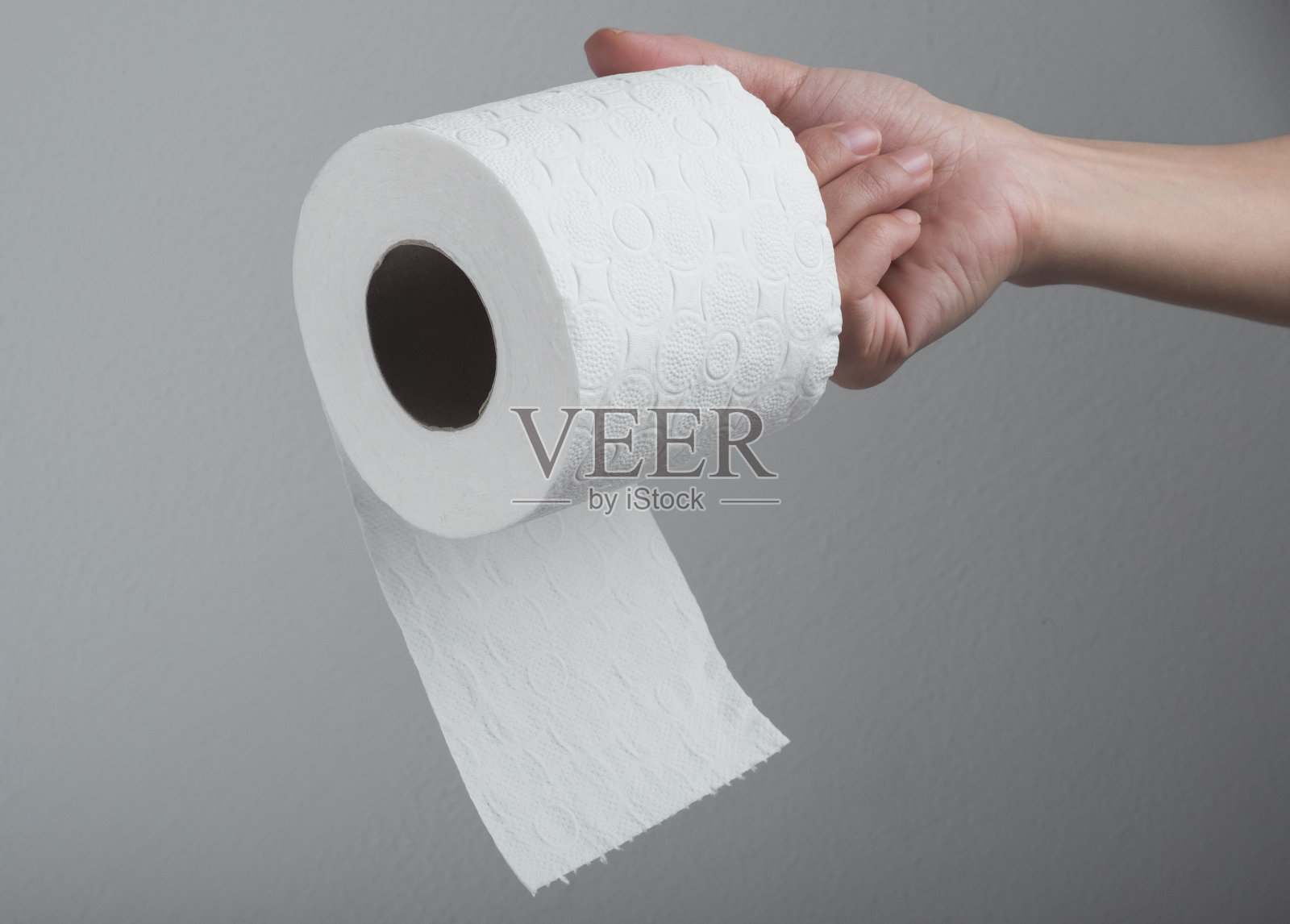 手拿白色卫生纸卷在灰色的背景照片摄影图片