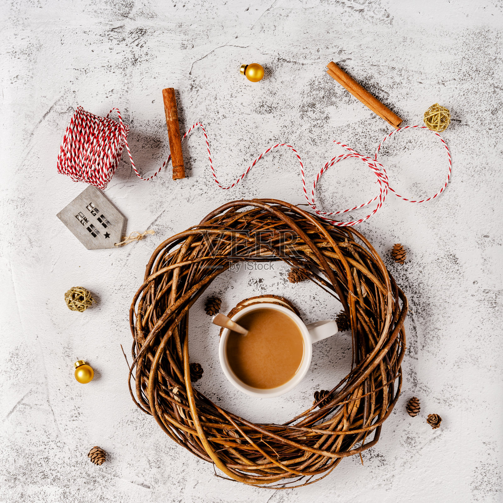 木制桌子上,热的节日咖啡饮料被圣诞物品包围着。红色围巾上的智能手机。舒适的假期和新年的概念。照片摄影图片