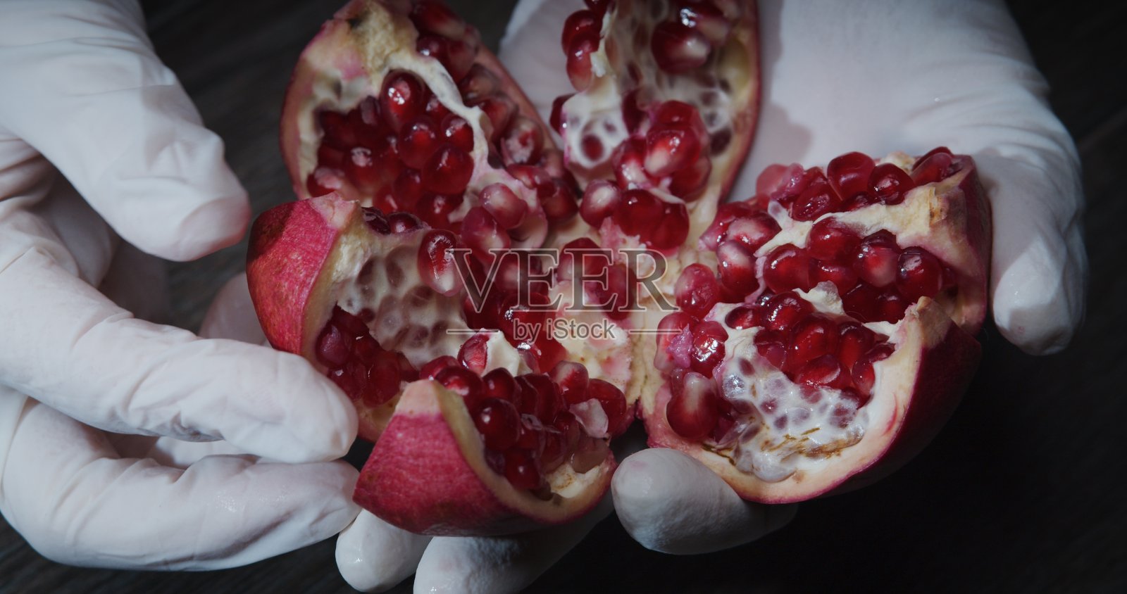 戴着手套的人手正在打破一个石榴——一步一步地用石榴、苏打水和迷迭香制作圣诞鸡尾酒照片摄影图片