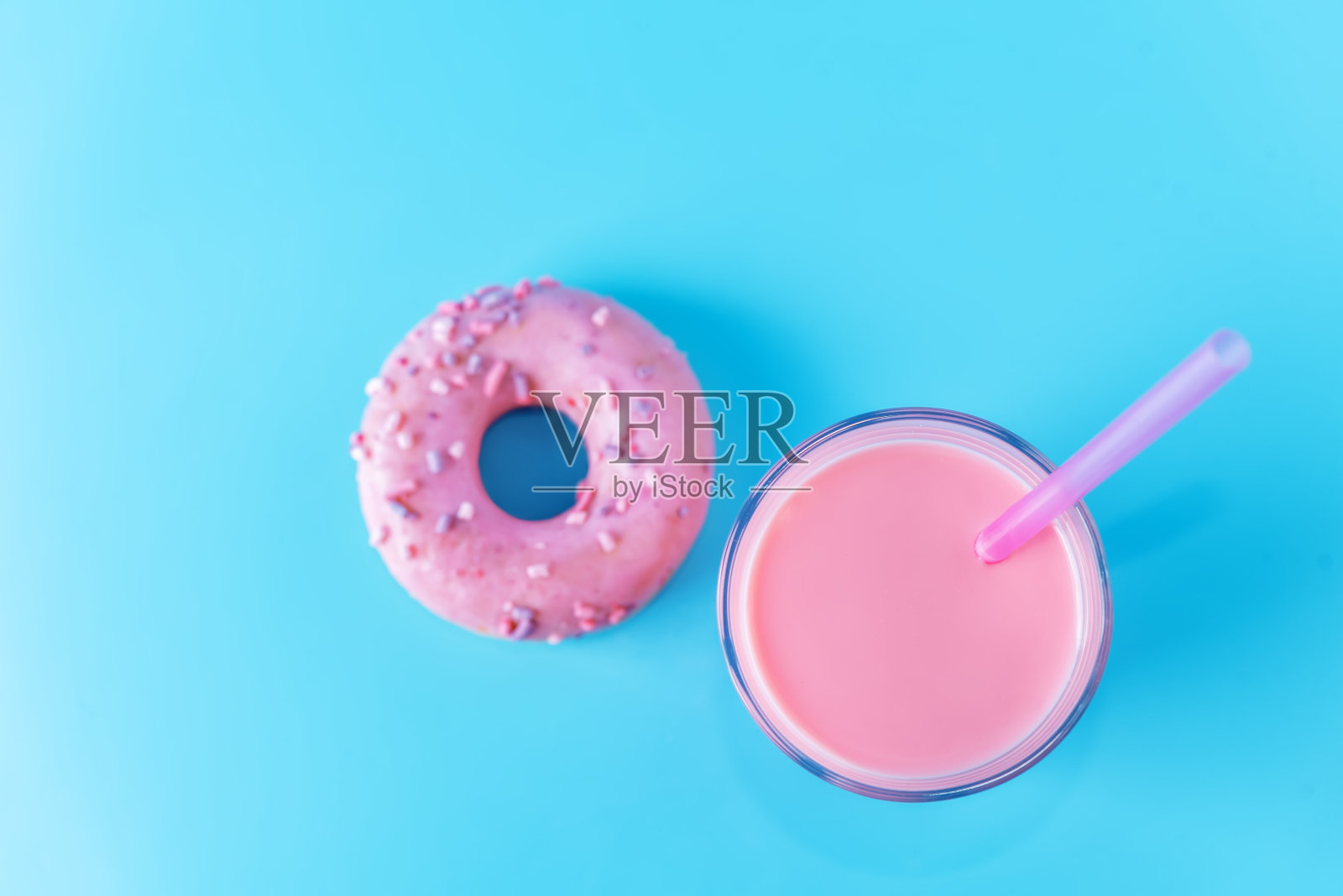 杯中的粉色牛奶鸡尾酒,蓝色背景上的粉色甜甜圈照片摄影图片