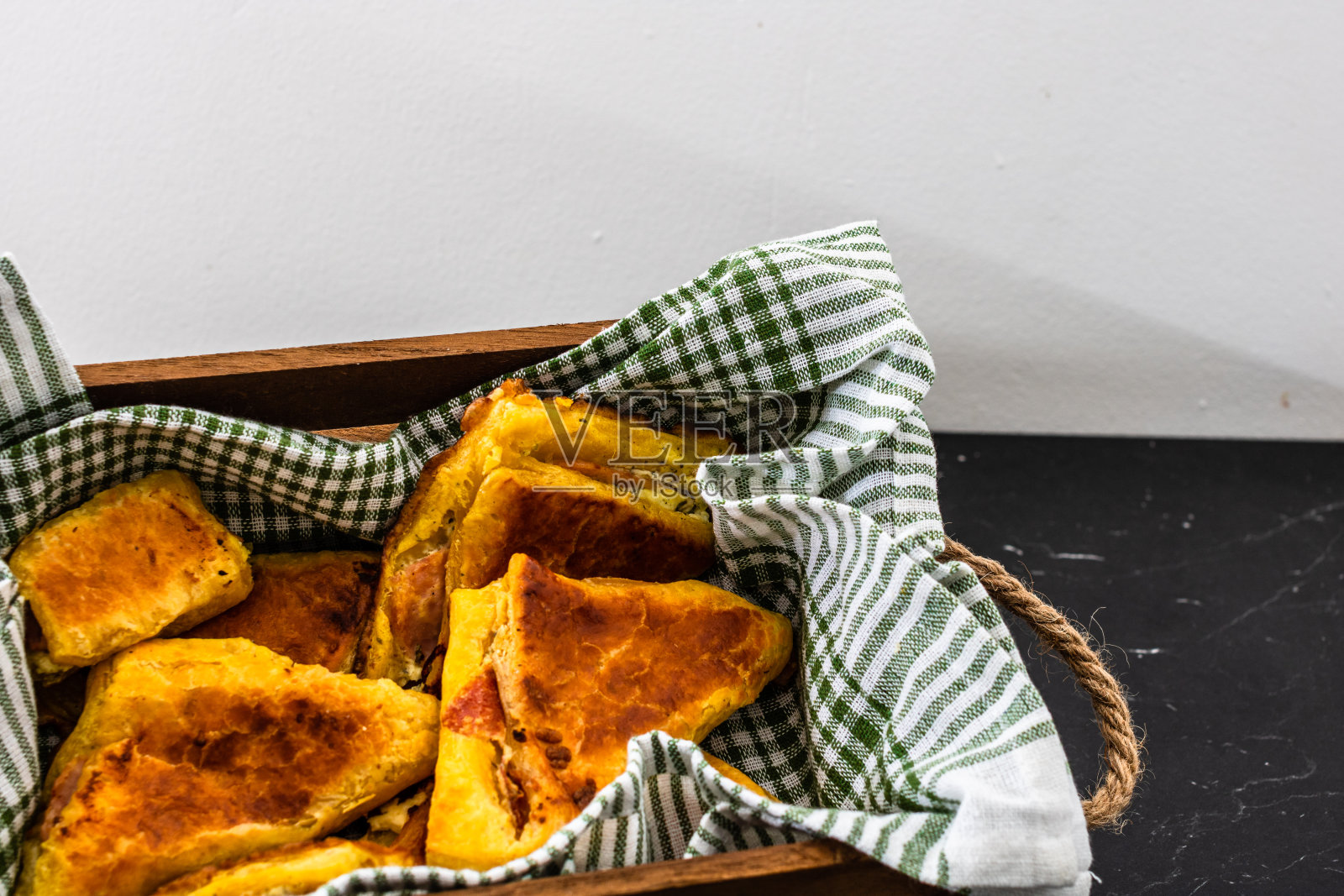 新鲜烘烤的自制火腿和芝士酥皮放在乡下的板条箱里。照片摄影图片