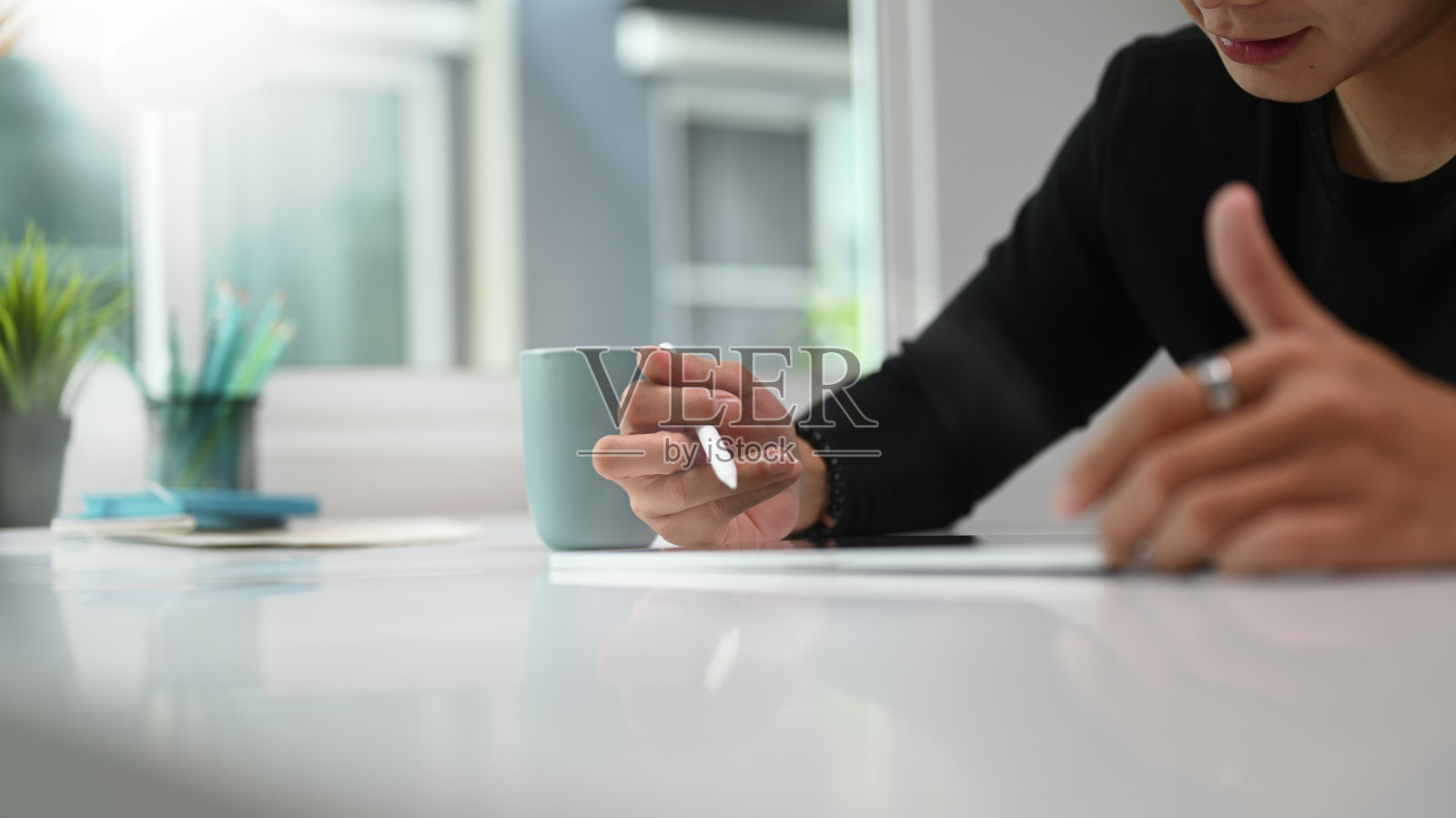 一名男子平面设计师正在工作空间使用平板电脑和手写笔。照片摄影图片