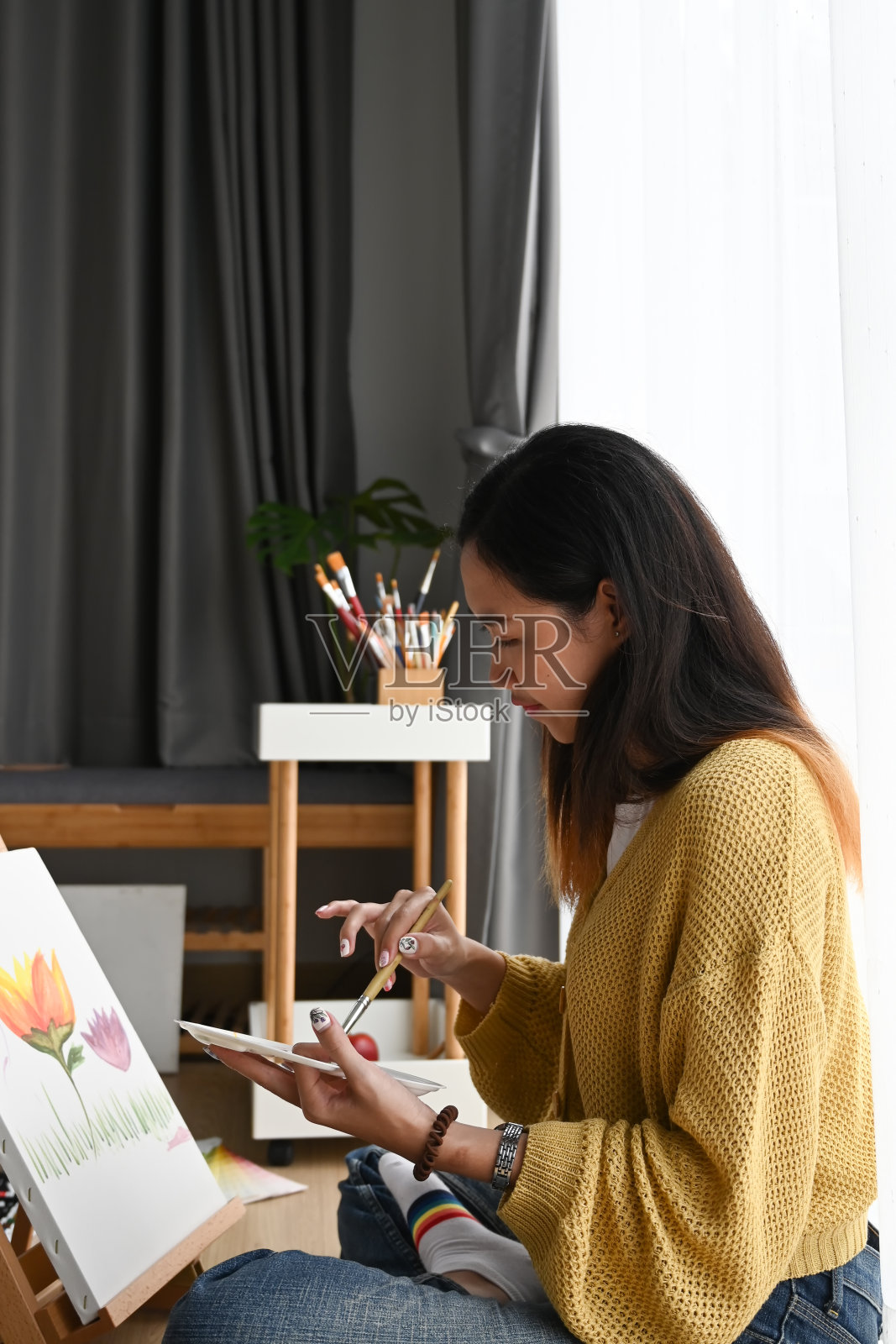 一个年轻女子的肖像在工作室地板上的帆布上画着。照片摄影图片