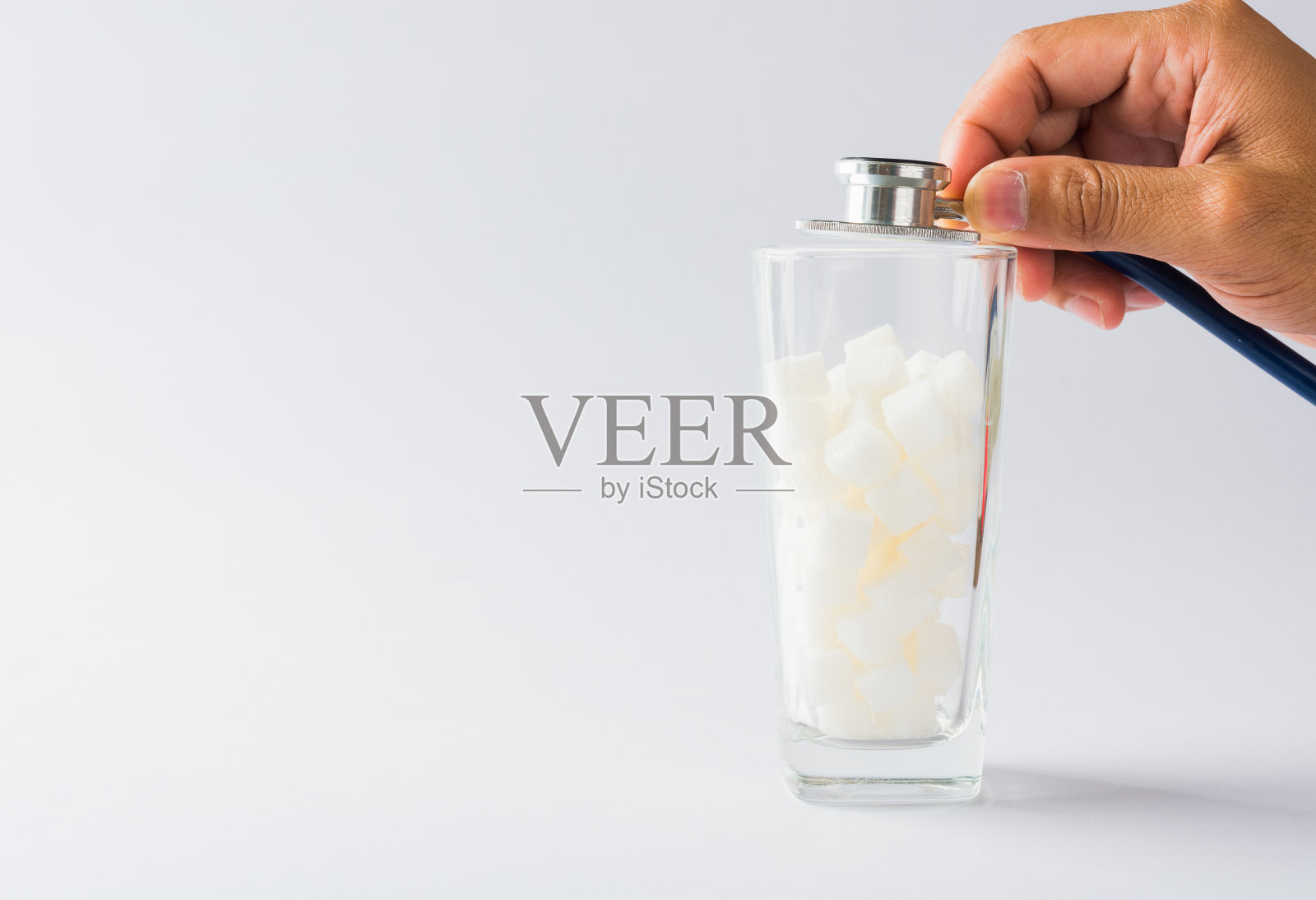 医生手持听诊器检查玻璃上满是白糖块照片摄影图片