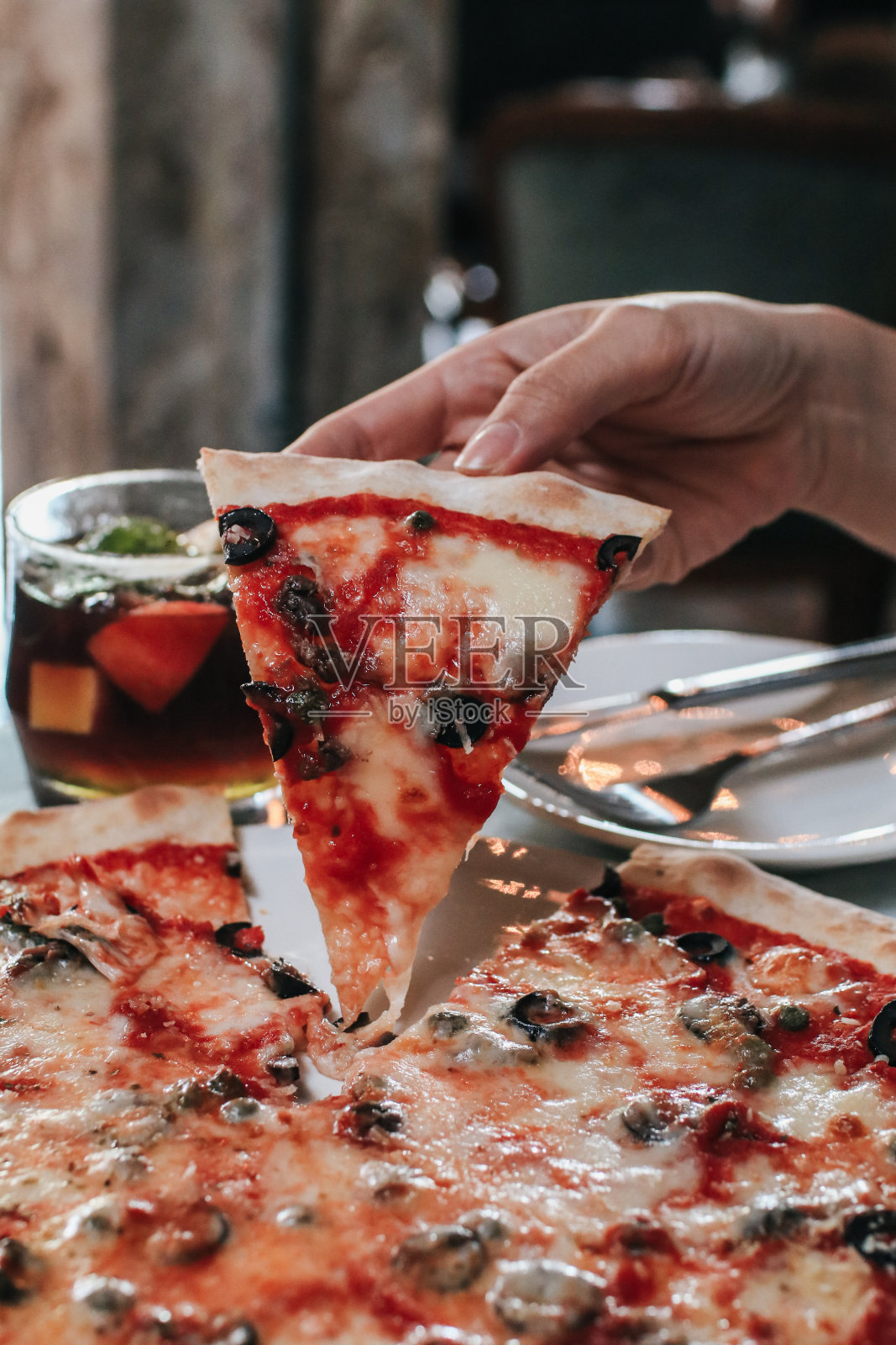 手工采摘美味的橄榄披萨片。在家开派对,吃披萨,玩得开心。休闲、餐饮、人与假日概念照片摄影图片