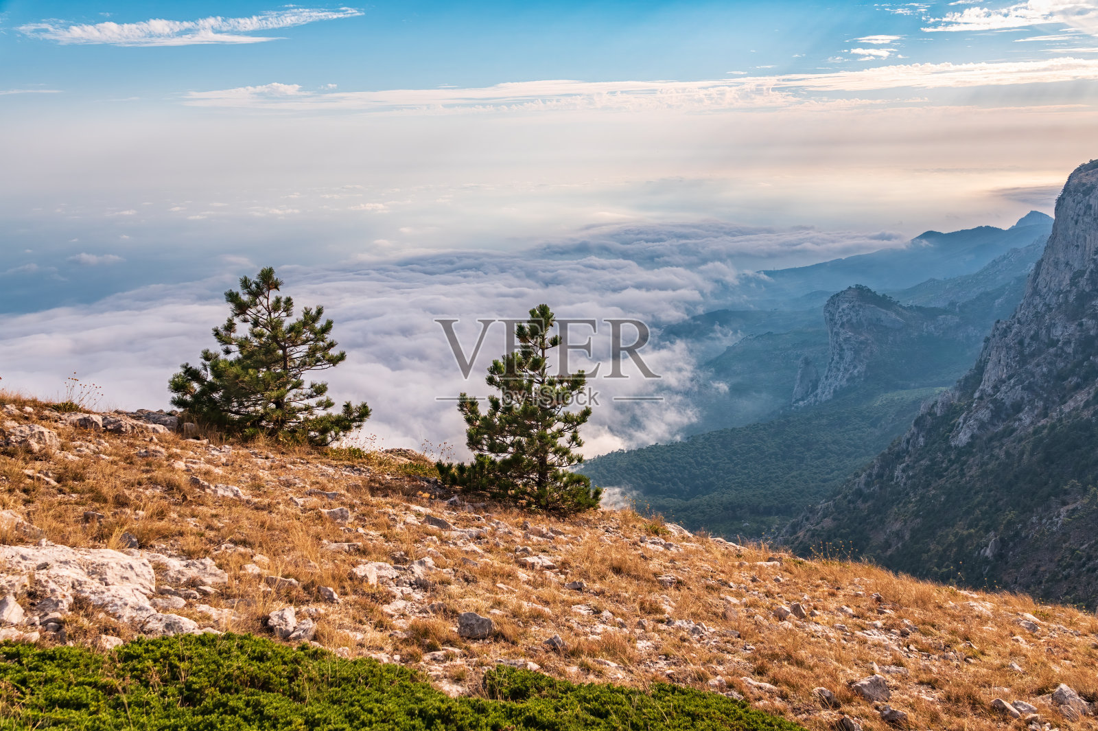 壮丽的落基山脉和峡谷在雾和云。夕阳的余晖笼罩着山谷。风景如画,富丽堂皇。克里米亚山脉上朦胧的日落照片摄影图片