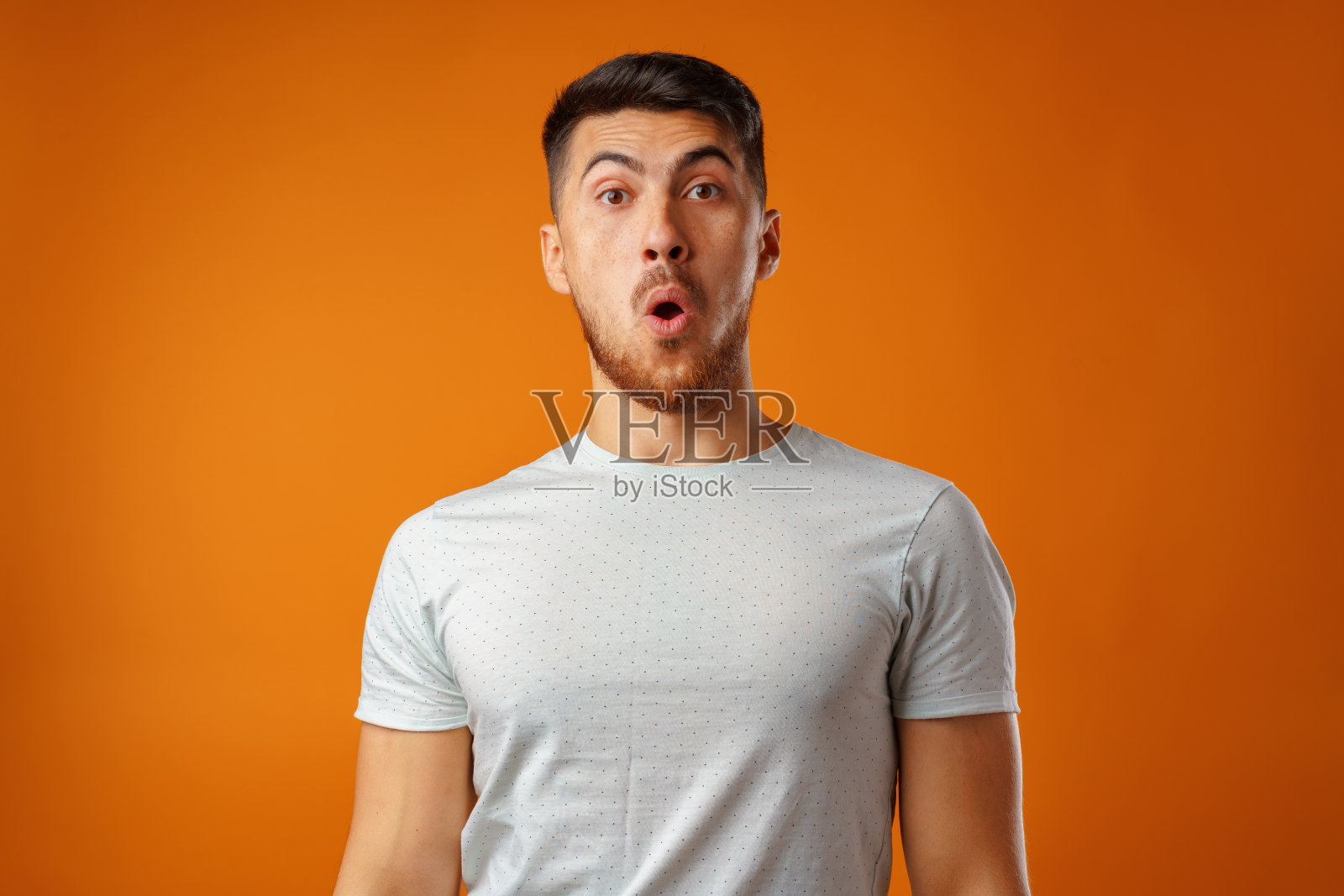 惊愕和困惑的胡子年轻人看起来惊讶。照片摄影图片