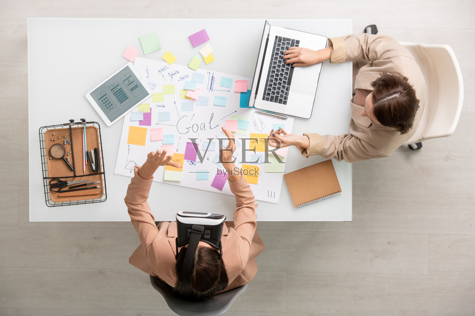 年轻的女商人用笔记本电脑与同事在虚拟现实头盔咨询照片摄影图片