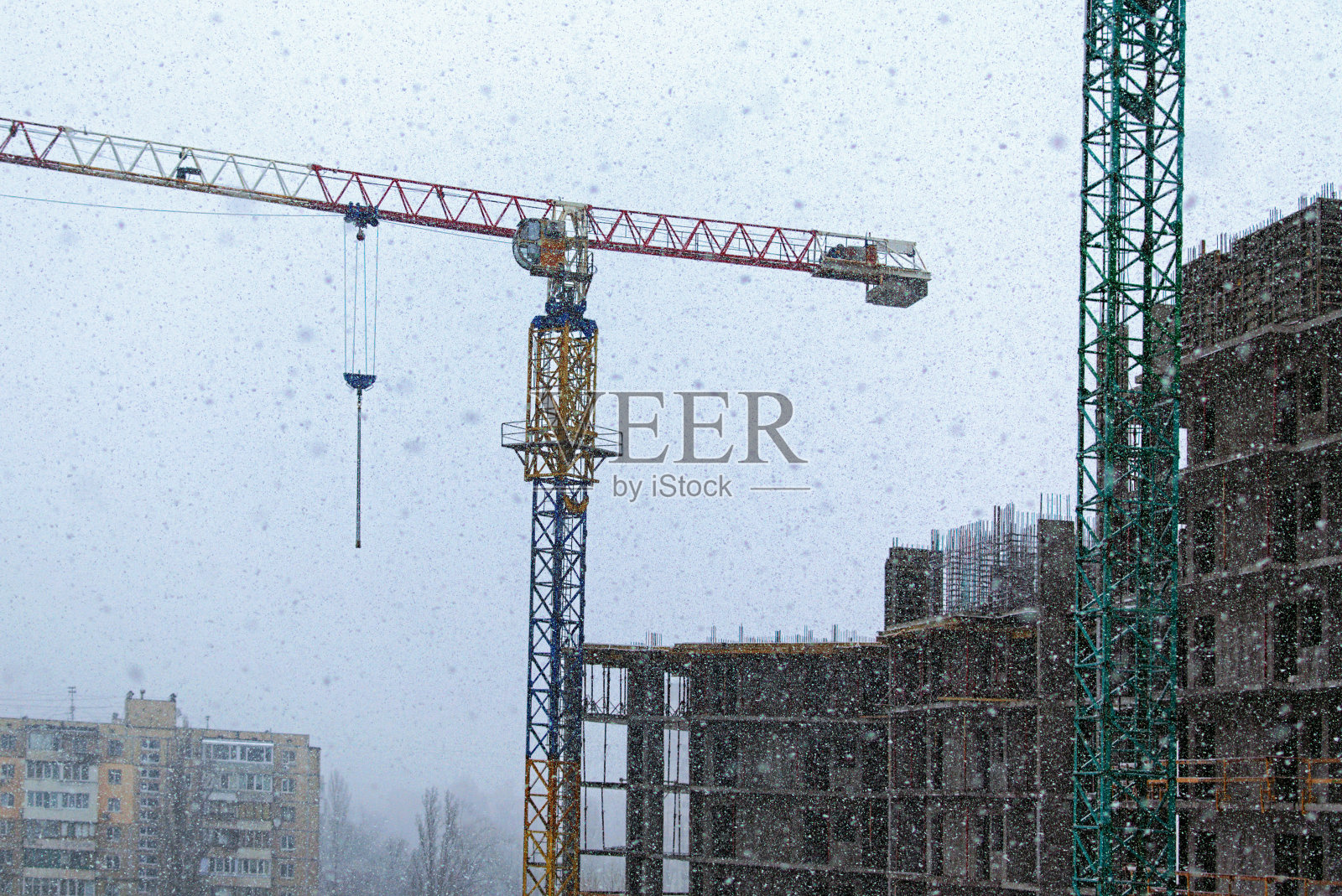 降雪期间未完工的建筑,近景。多云的天空下,新多层建筑的混凝土顶层。现代混凝土结构,在建建筑。抽象的背景照片摄影图片