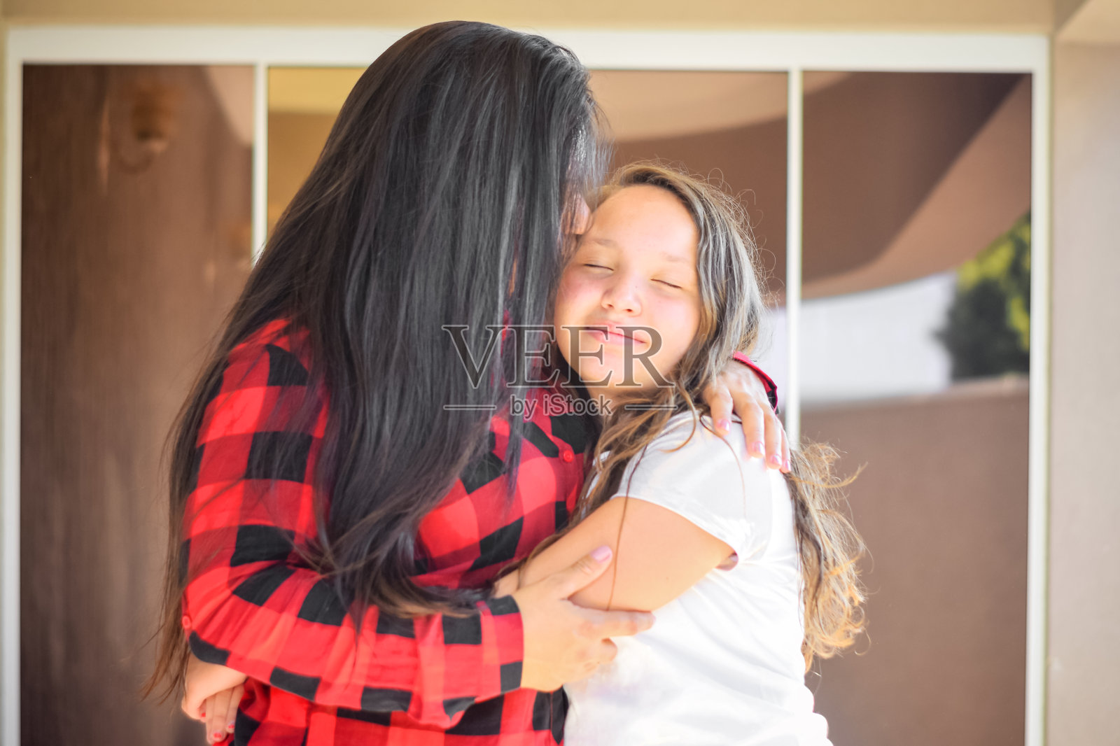 年轻的母亲亲吻她的女儿照片摄影图片