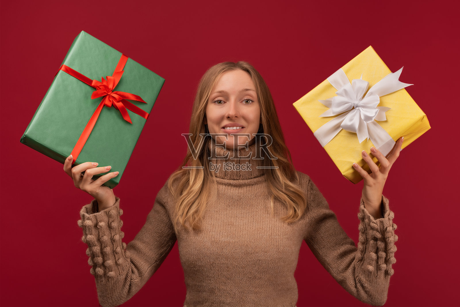 迷人的年轻金发女人拿着很多礼品盒。工作室拍摄红色背景。新年生日假期概念照片摄影图片