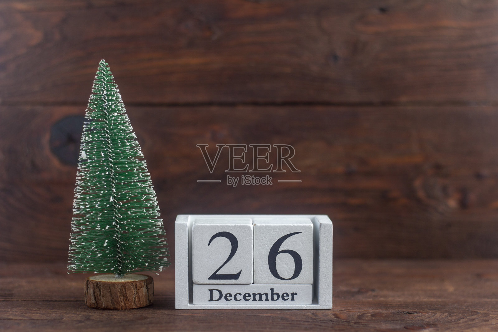 农历十二月二十六日。木制背景上有一棵小圣诞树的日历。冬天。文本的空白。照片摄影图片