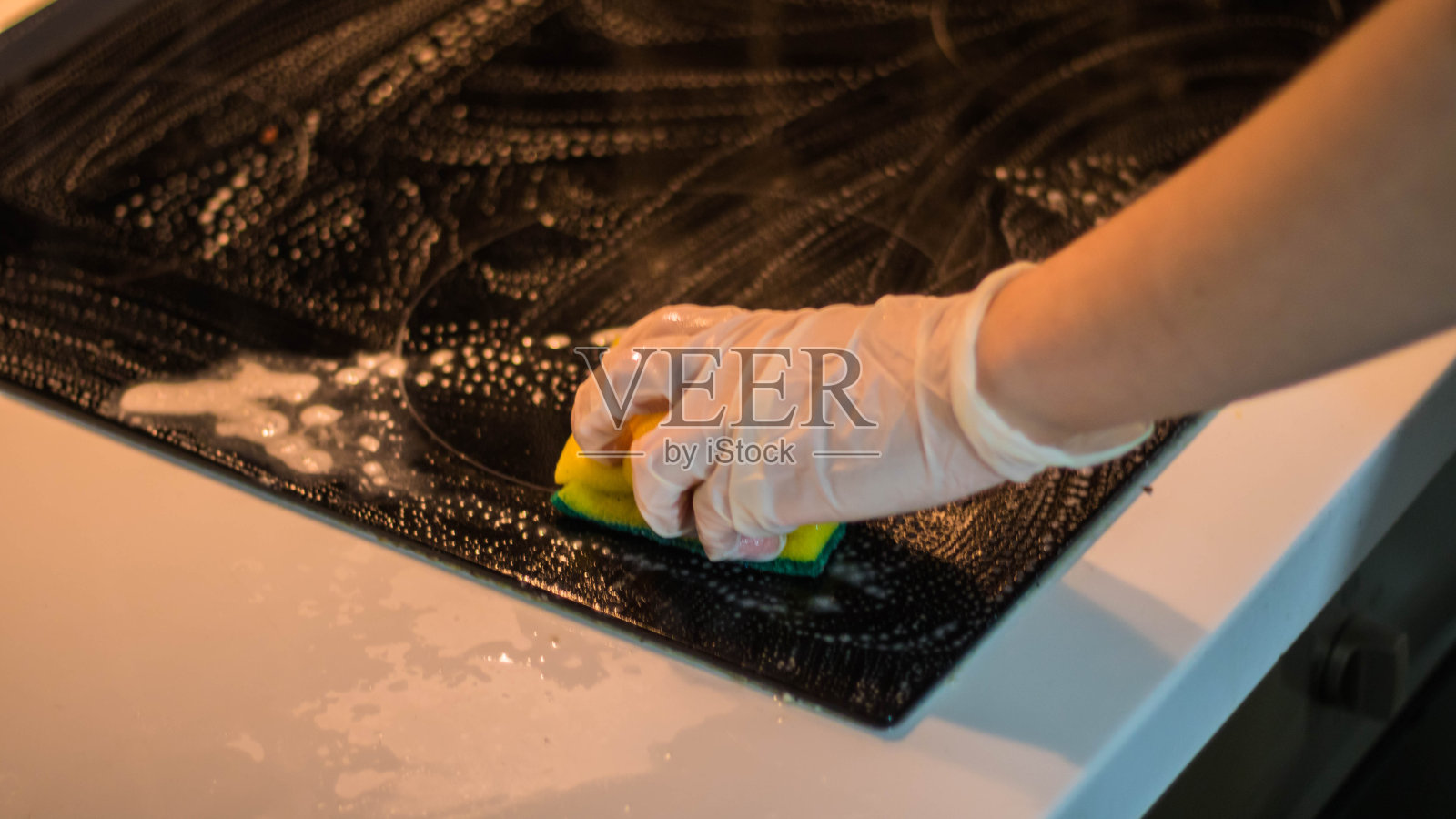 戴着手套用海绵擦拭厨房的人照片摄影图片