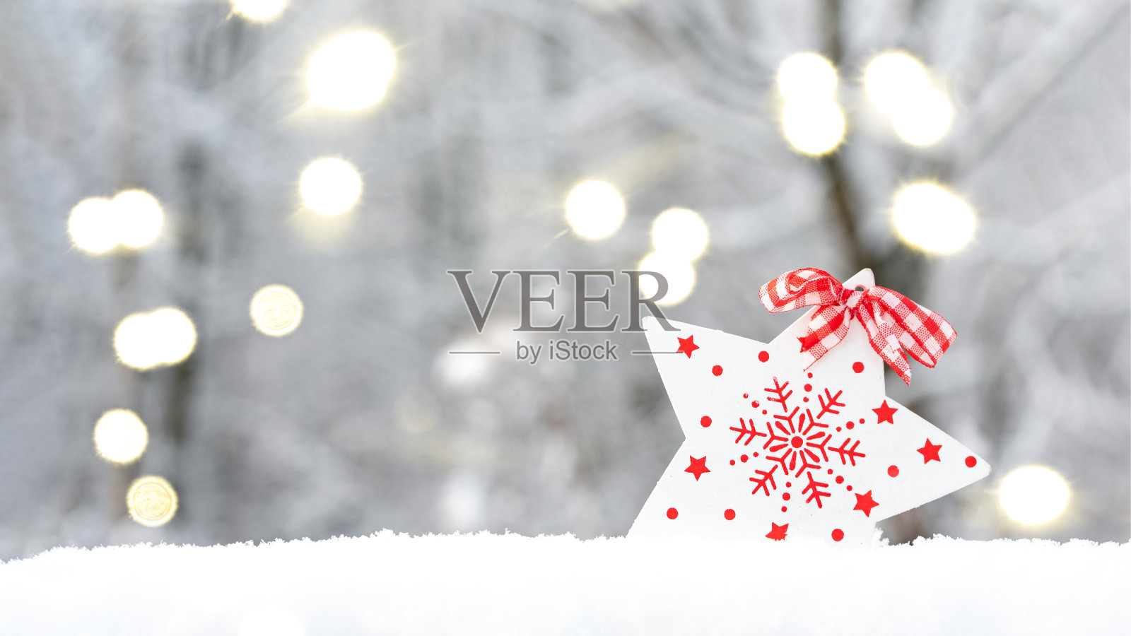 圣诞之星上的雪,在一个模糊的冬天背景与散景灯。假日贺卡与文字的地方。副本的空间。照片摄影图片