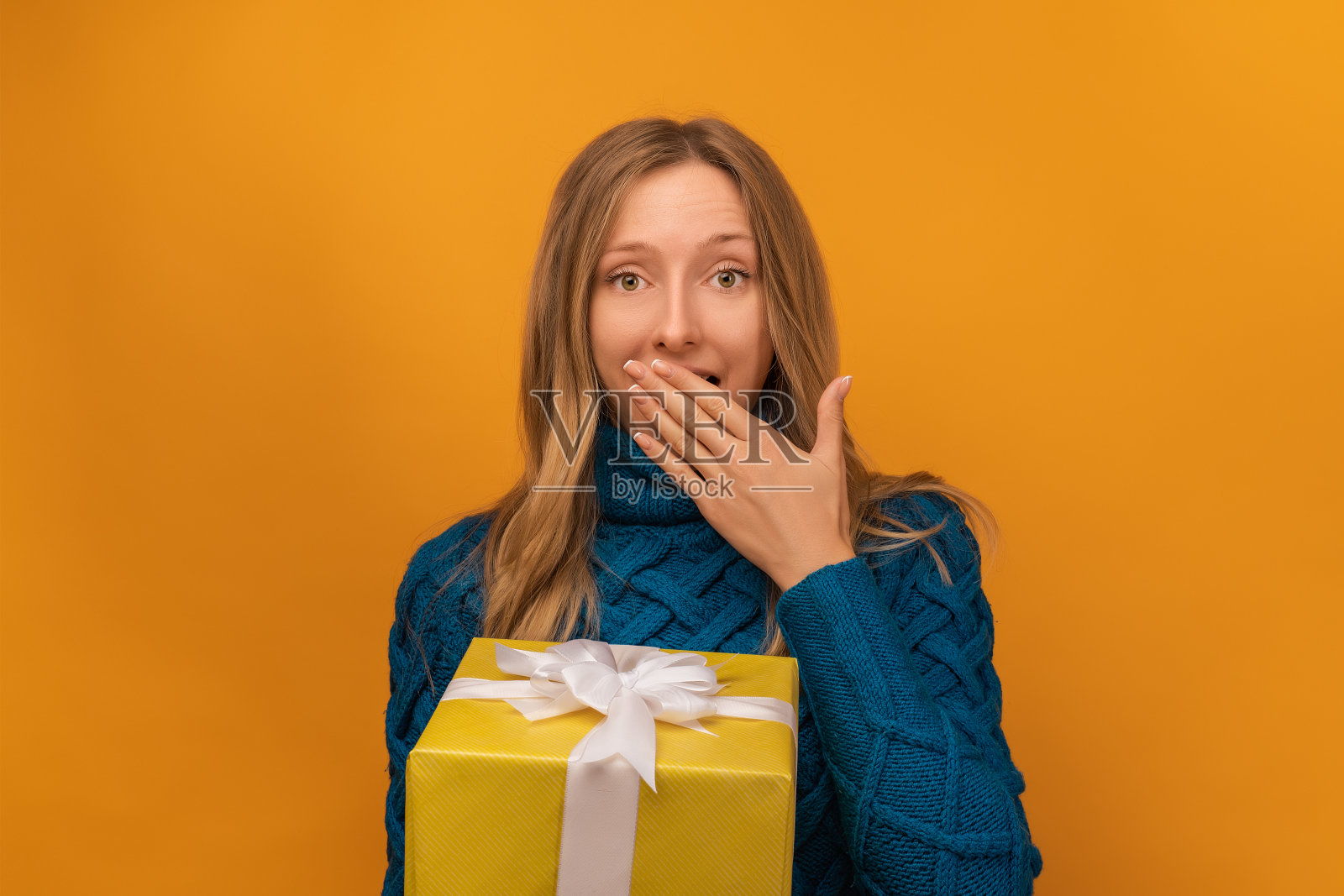 迷人的年轻女子与礼品装饰丝带与惊讶的脸表情在黄色的背景照片摄影图片