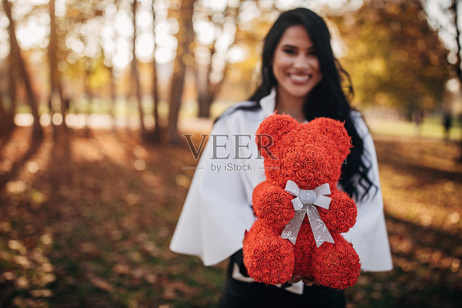 在公园里抱着红色泰迪熊的女人照片摄影图片