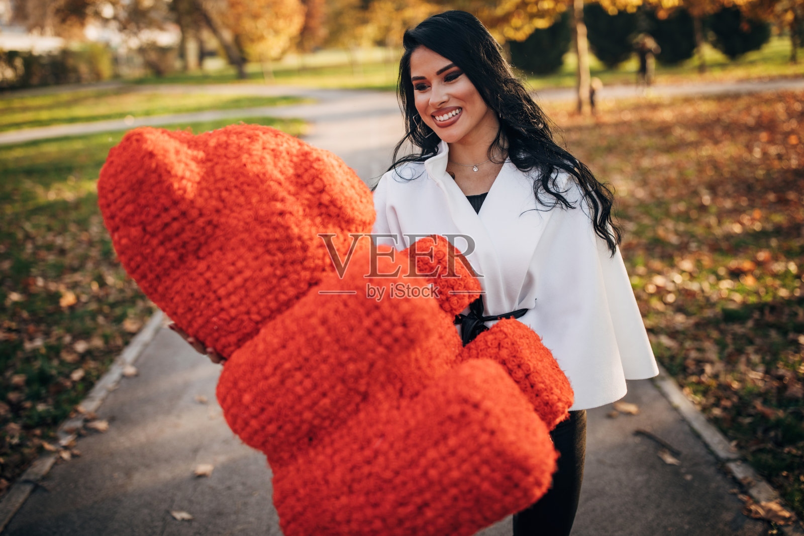 美丽的女人在公园里抱着红色的大泰迪熊照片摄影图片