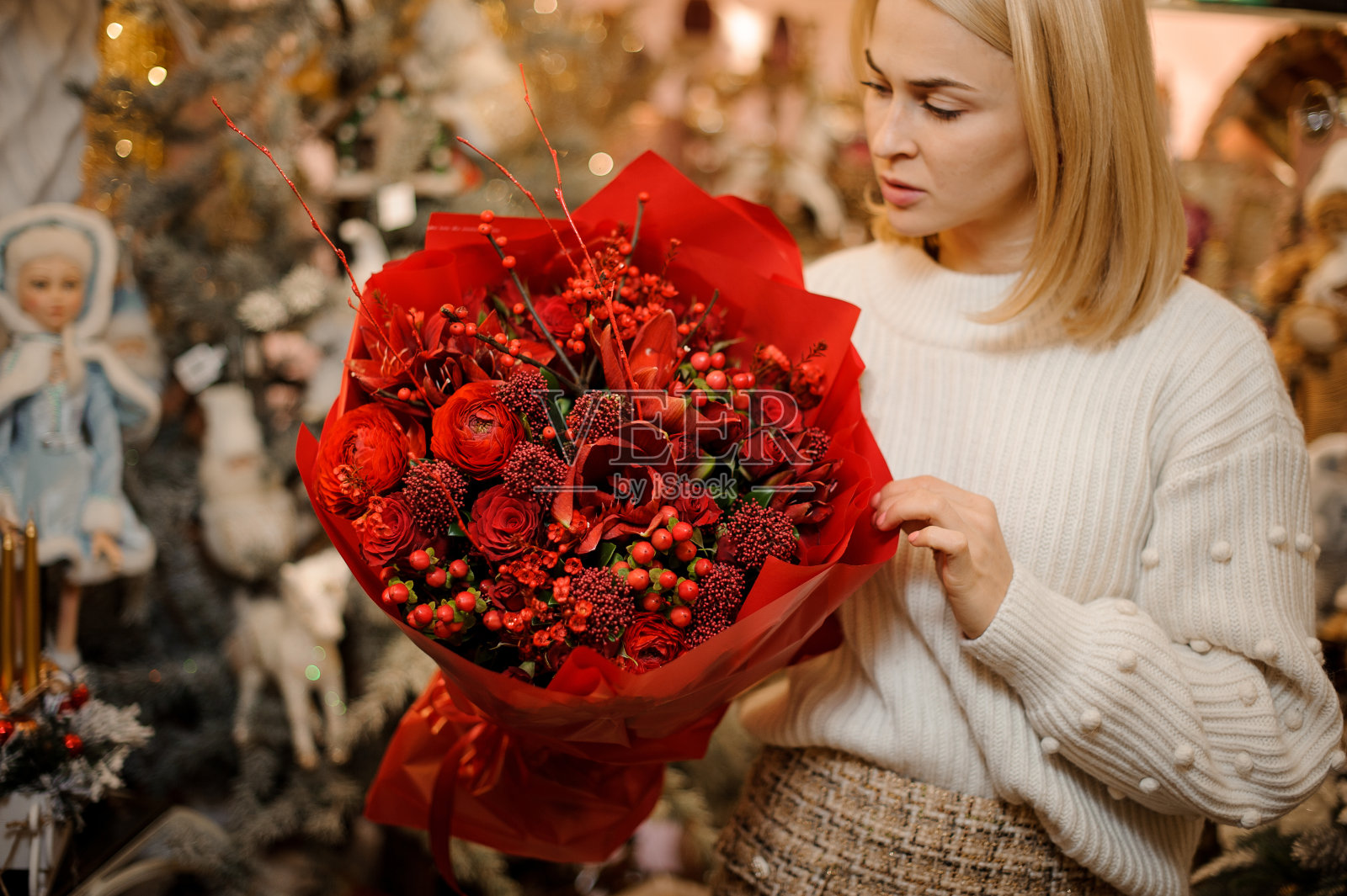 美丽的女人拿着不同的红色鲜花和红色浆果的鲜艳花束照片摄影图片