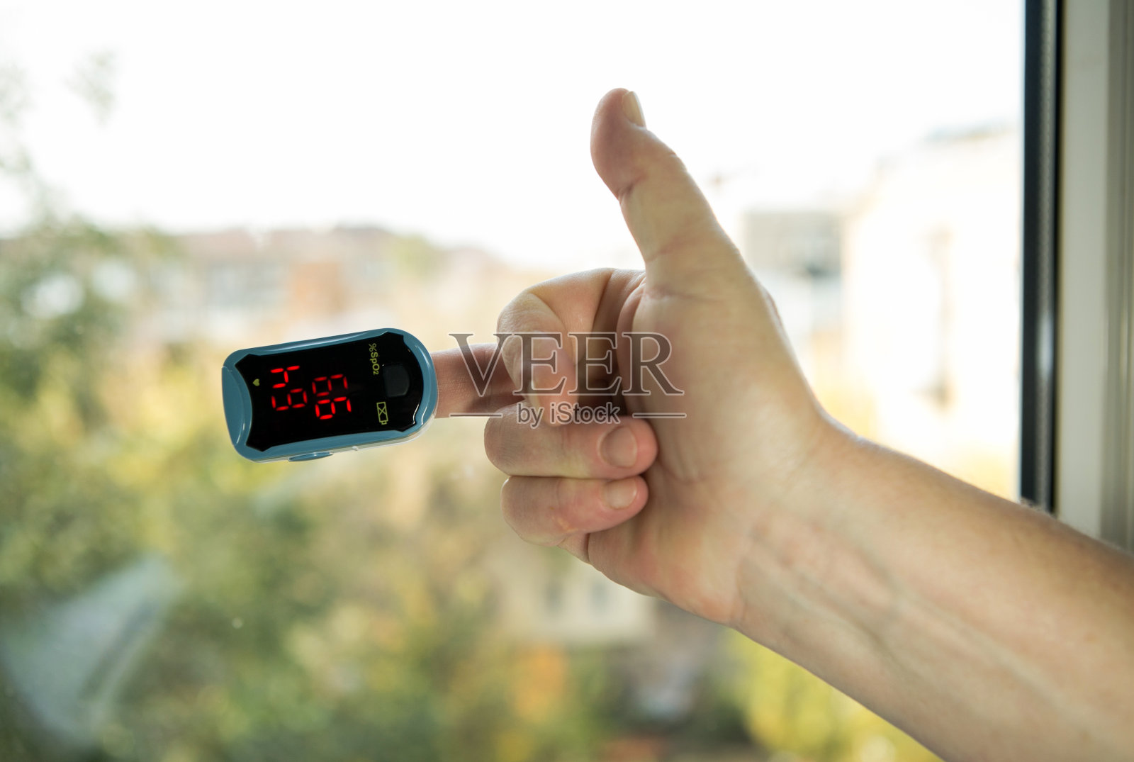 血氧饱和度是冠状病毒大流行背景下最重要的健康状况指标。人的手,手指上有脉搏血氧计。的手势。照片摄影图片