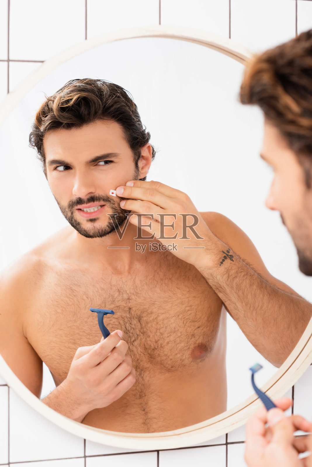 赤裸上身的男人触摸脸颊的伤口和拿着剃刀近镜模糊的前景照片摄影图片