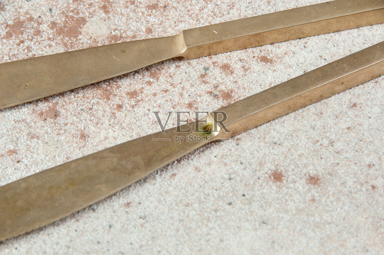 混凝土背景上的两把旧青铜刀。照片摄影图片