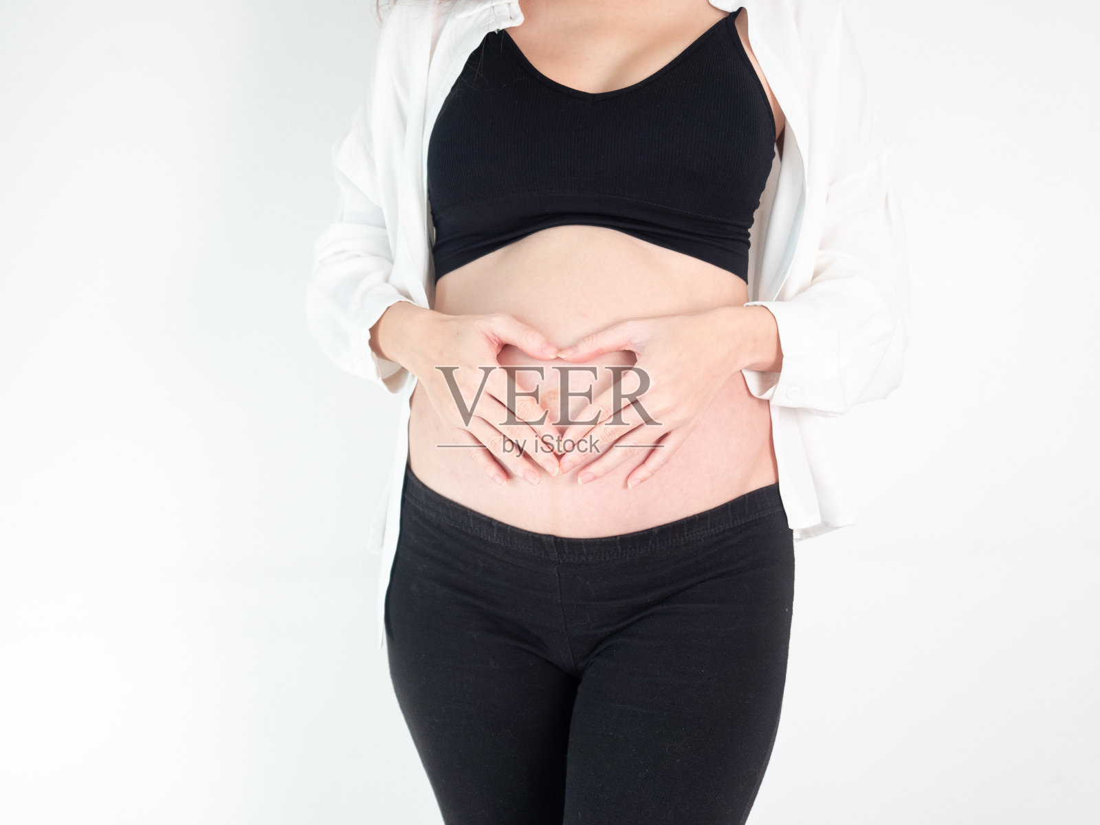 肖像7个月怀孕的亚洲妇女在白色的床房间,女人触摸她的腹部腹部在白色的背景。照片摄影图片