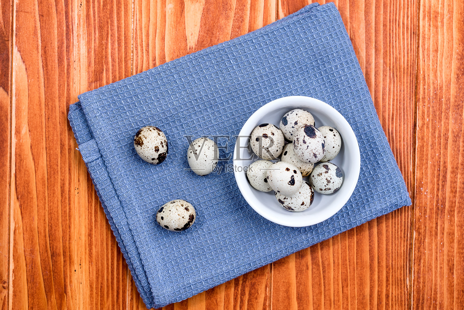 鹌鹑蛋在白色陶瓷碗上,蓝色厨房布照片摄影图片