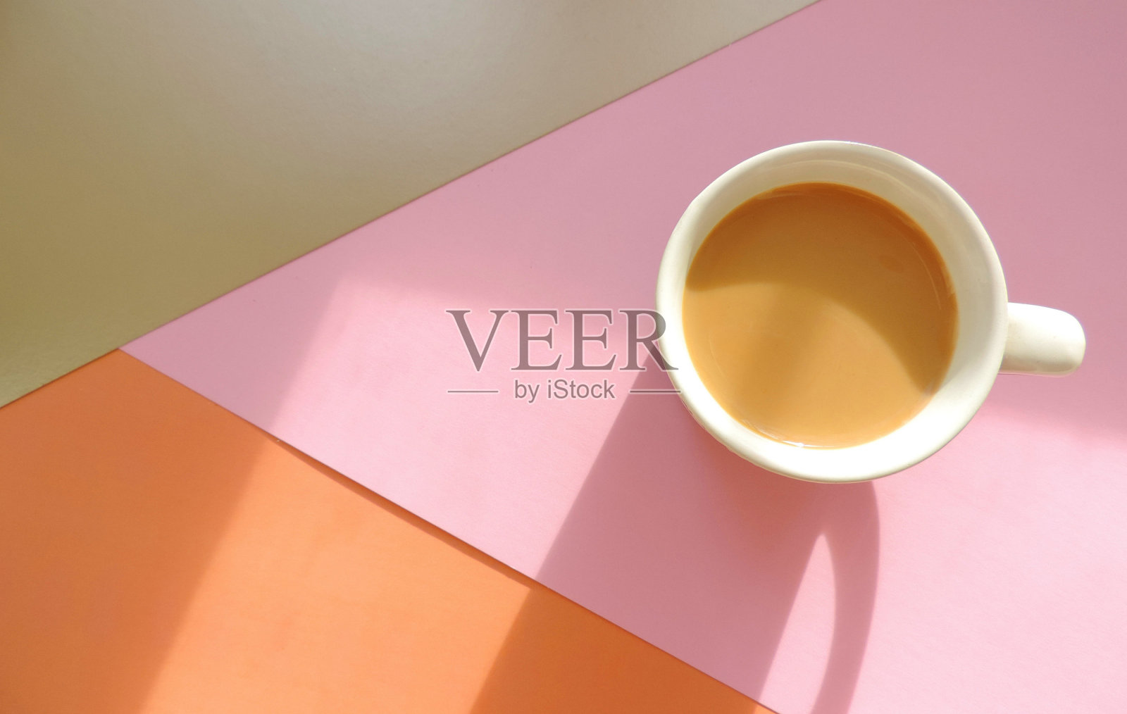 一杯淡粉色的咖啡,背景是沙影,早上好。自然晴朗的早晨光线和长长的阴影。俯视图照片摄影图片