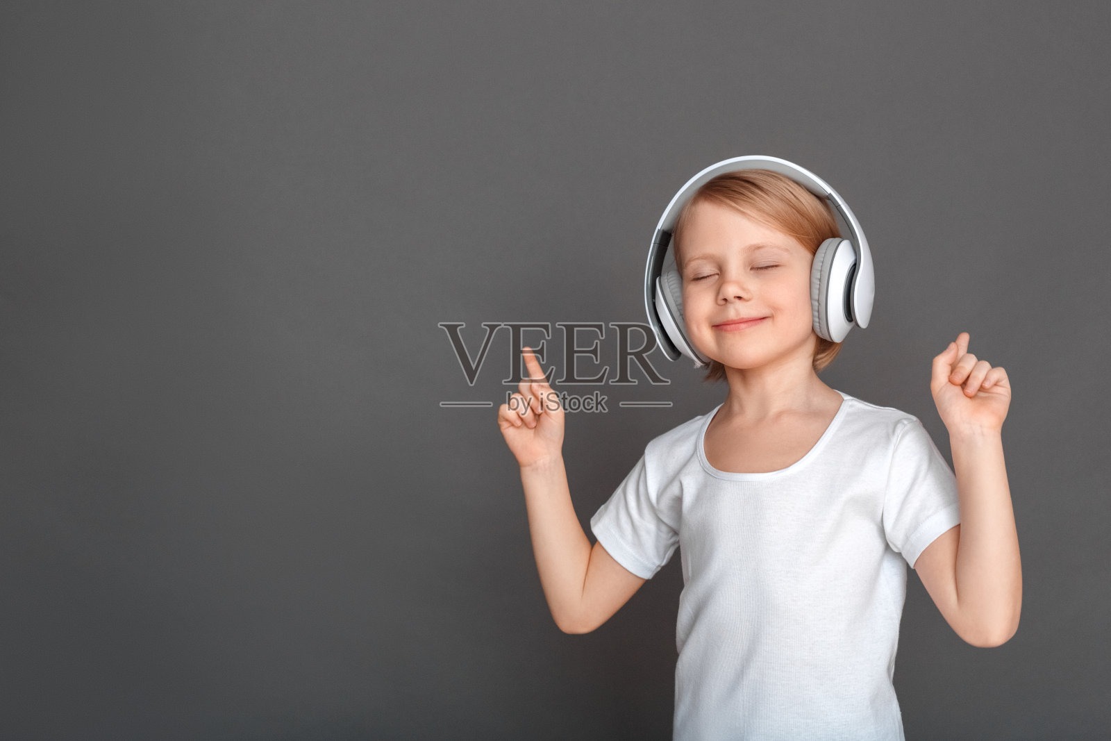 自由泳。小女孩戴着耳机孤立地听着灰色的歌曲,闭着眼睛指挥着悦耳的音乐照片摄影图片