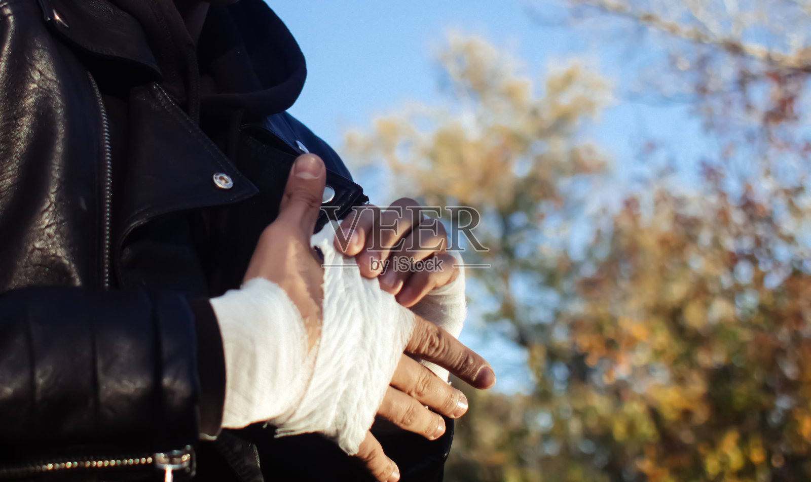 拳击手正在用绷带包扎他的双手。准备格斗、体育比赛、拳击和跆拳道的概念。一个穿皮夹克的男人。照片摄影图片