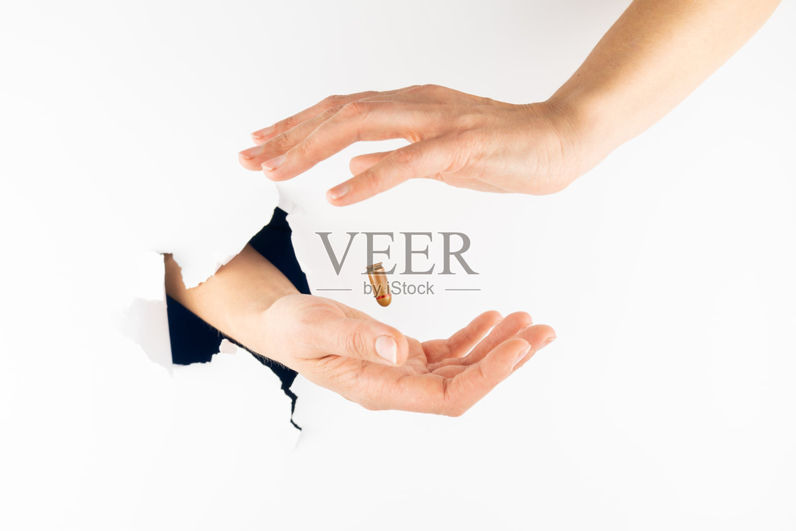 手枪的弹壳在那个女人的双手之间盘旋,一只手插在白墙上的洞里。照片摄影图片