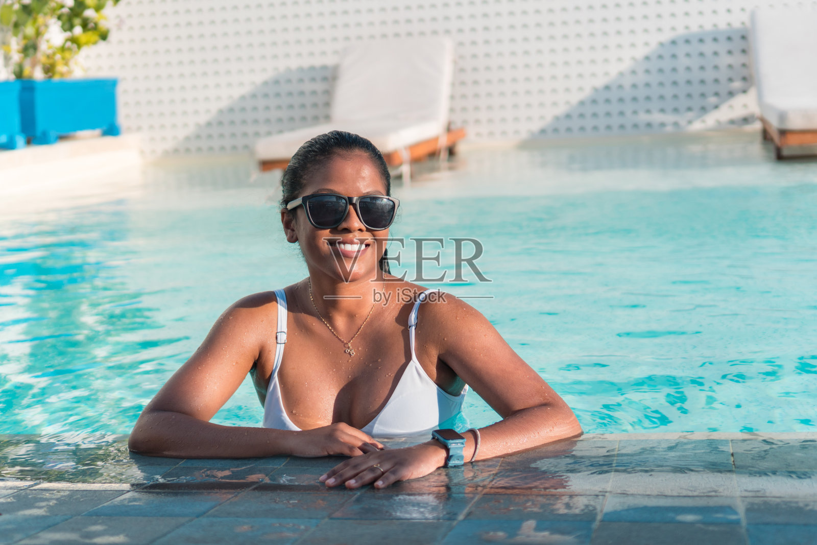 美丽的女人在豪华的泳池边放松。在旅游温泉度假村的女孩照片摄影图片