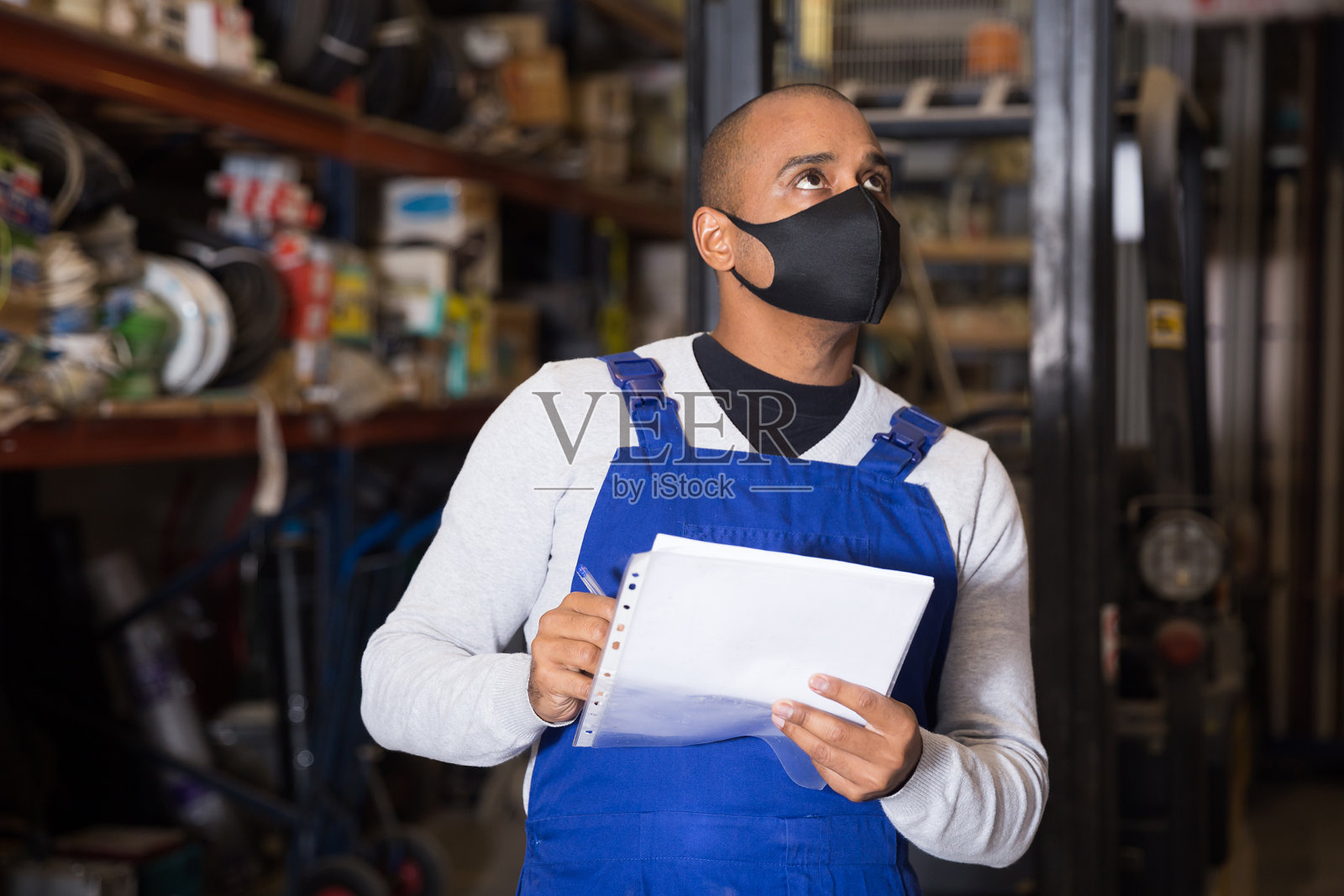 带防护口罩的仓库工人在清点建筑材料时做记录照片摄影图片