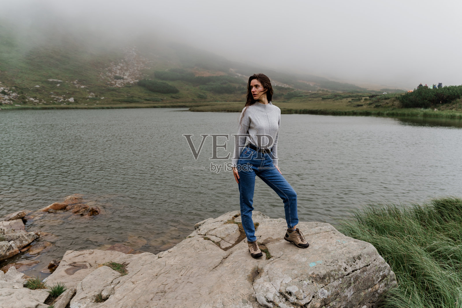 湖在山顶。雾蒙蒙的湖。女孩在岩石上摆姿势。照片摄影图片
