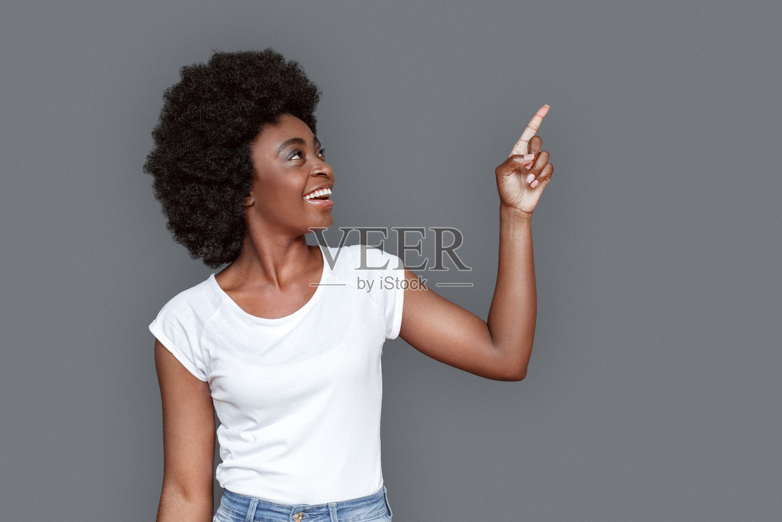 年轻女子站在孤立的指着墙高兴照片摄影图片