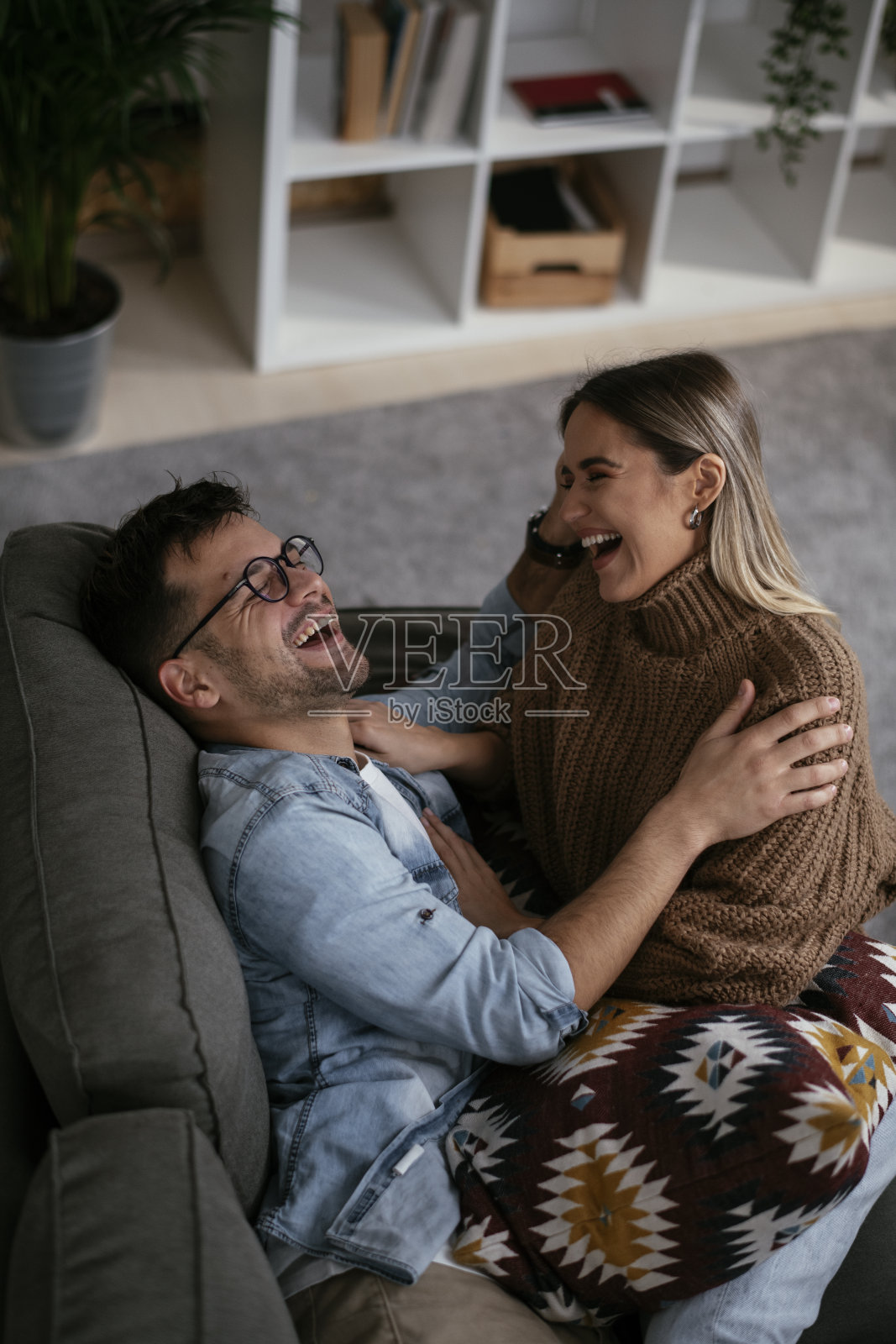 一对年轻的情侣一起在沙发上放松。照片摄影图片