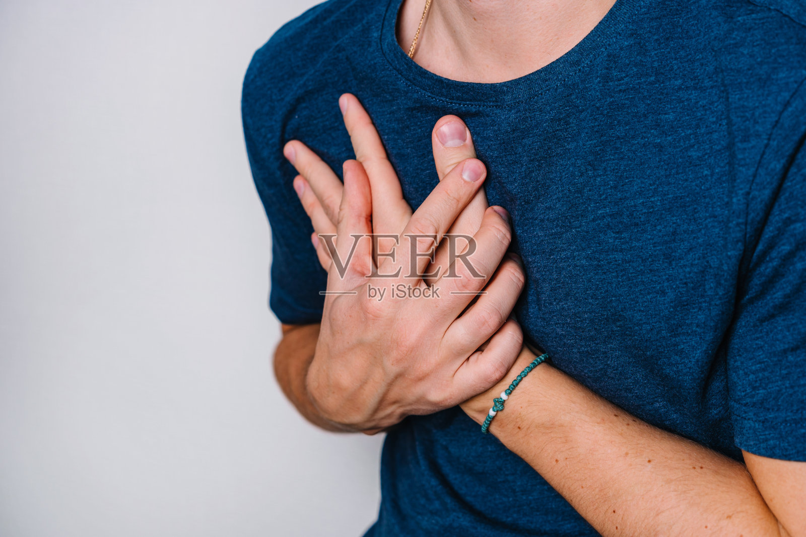 这个人感到心脏部位疼痛,用两只手捂着胸口。反流性疾病或心脏系统疾病的概念。白色背景上的文字空间照片摄影图片