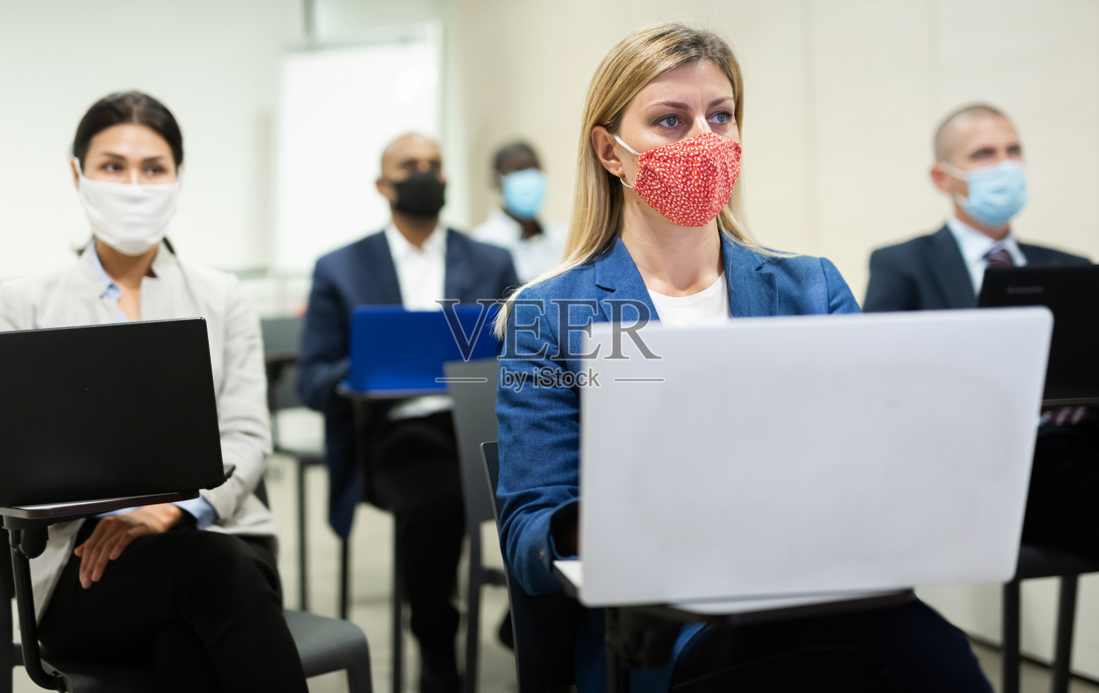 一群戴着防护面具的国际商务人士正在会议室的电脑上工作照片摄影图片