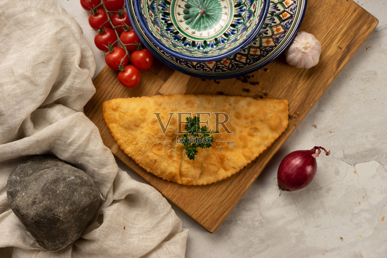 一道著名的俄罗斯菜是用肉、蔬菜和香草烹制的热腾腾的cheburek,旁边是带有传统图案的乌兹别克民族陶瓷菜肴。照片摄影图片